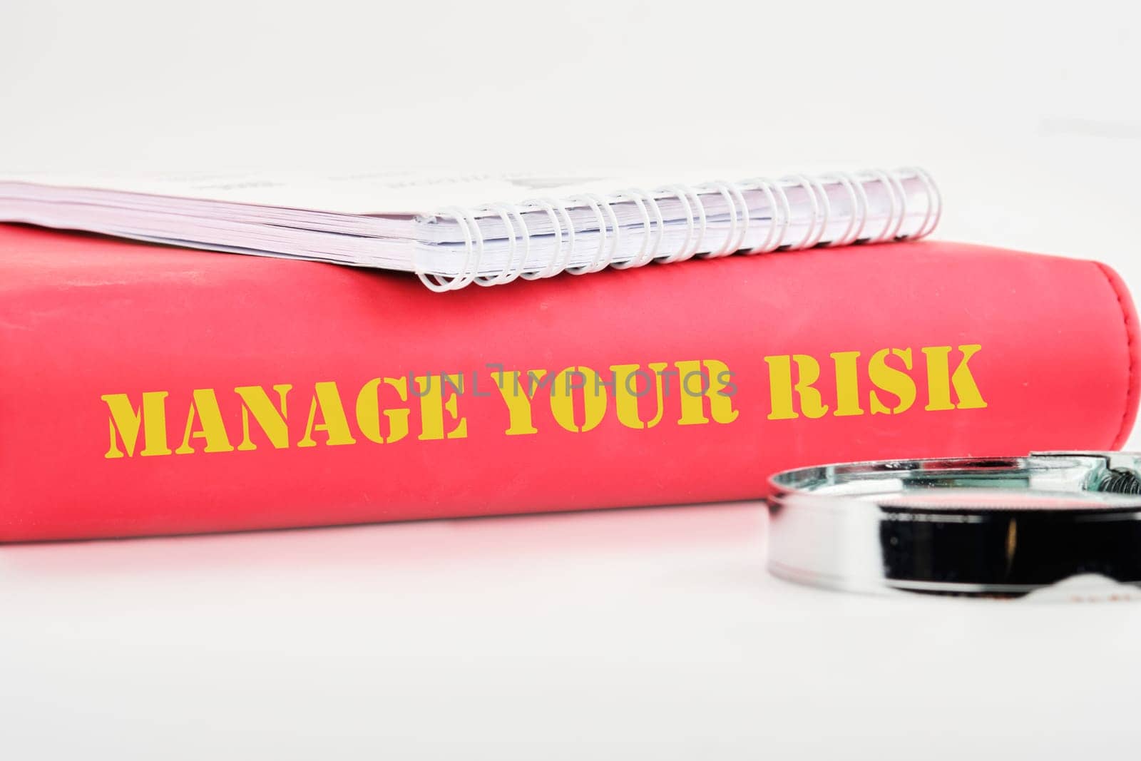 Business and manage your risk concept. Concept word Manage your risk on the back of the book cover, a notebook on a white background