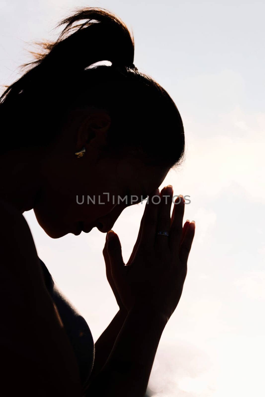 backlight portrait of young asian woman practicing yoga in pray position, concept of mental relaxation and healthy lifestyle