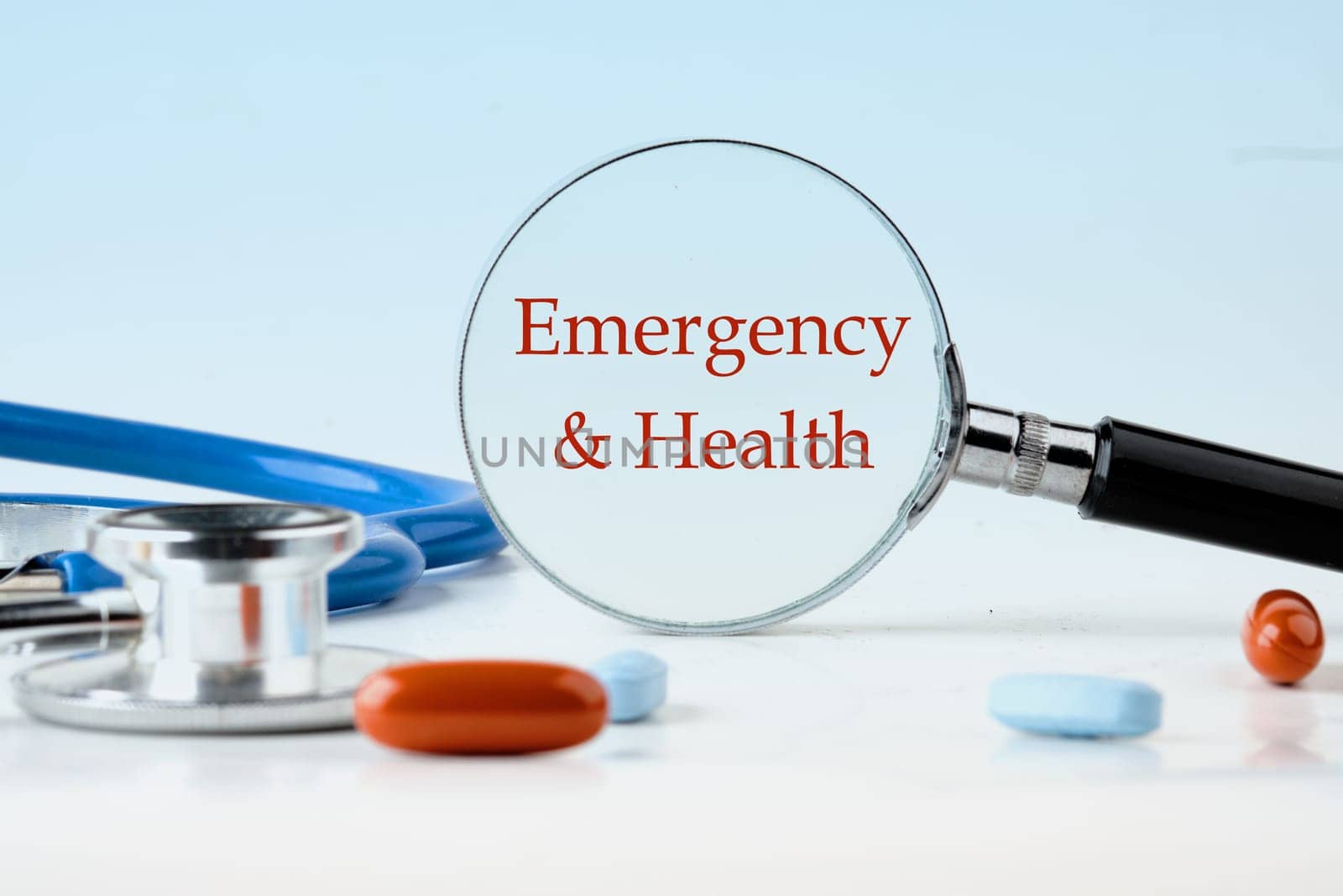 Medical concept. Emergency and Health text on a blue background through a magnifying glass