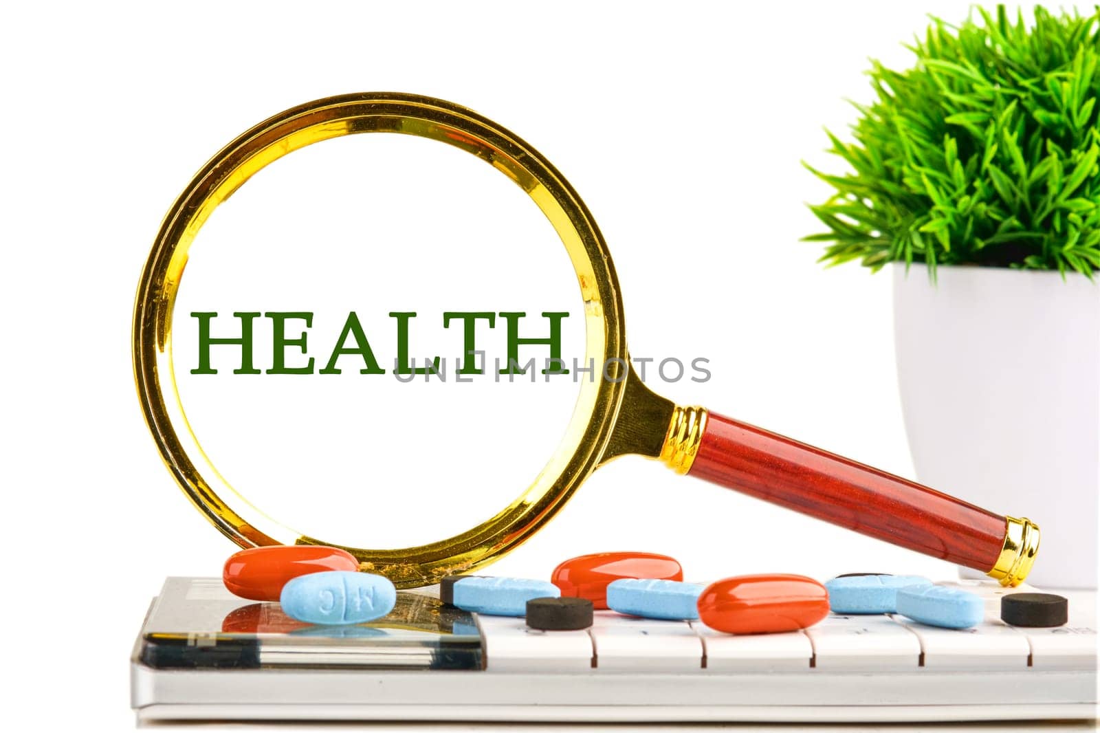 Investment in life insurance and healthcare concept. HEALTH through a magnifying glass on a white background on a calculator with a green plant and tablets, vitamins