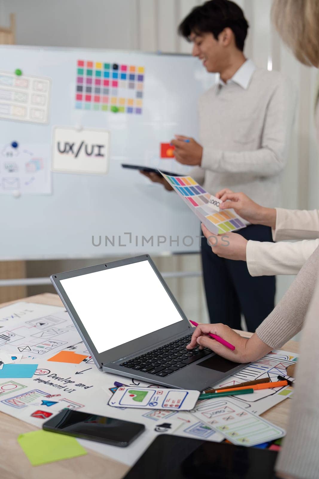 Designer team recommends color while mockup laptop display UI and UX designs for mobile app and website. Creative design and business concept.