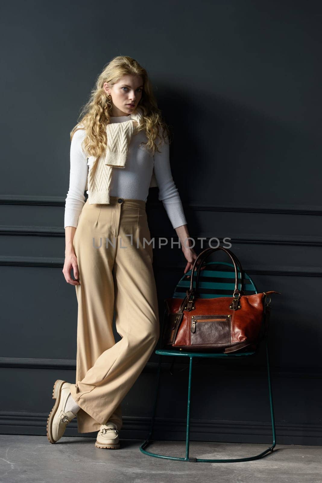 beautiful curly blond hair woman posing with a brown shopper bag near gray wall by Ashtray25