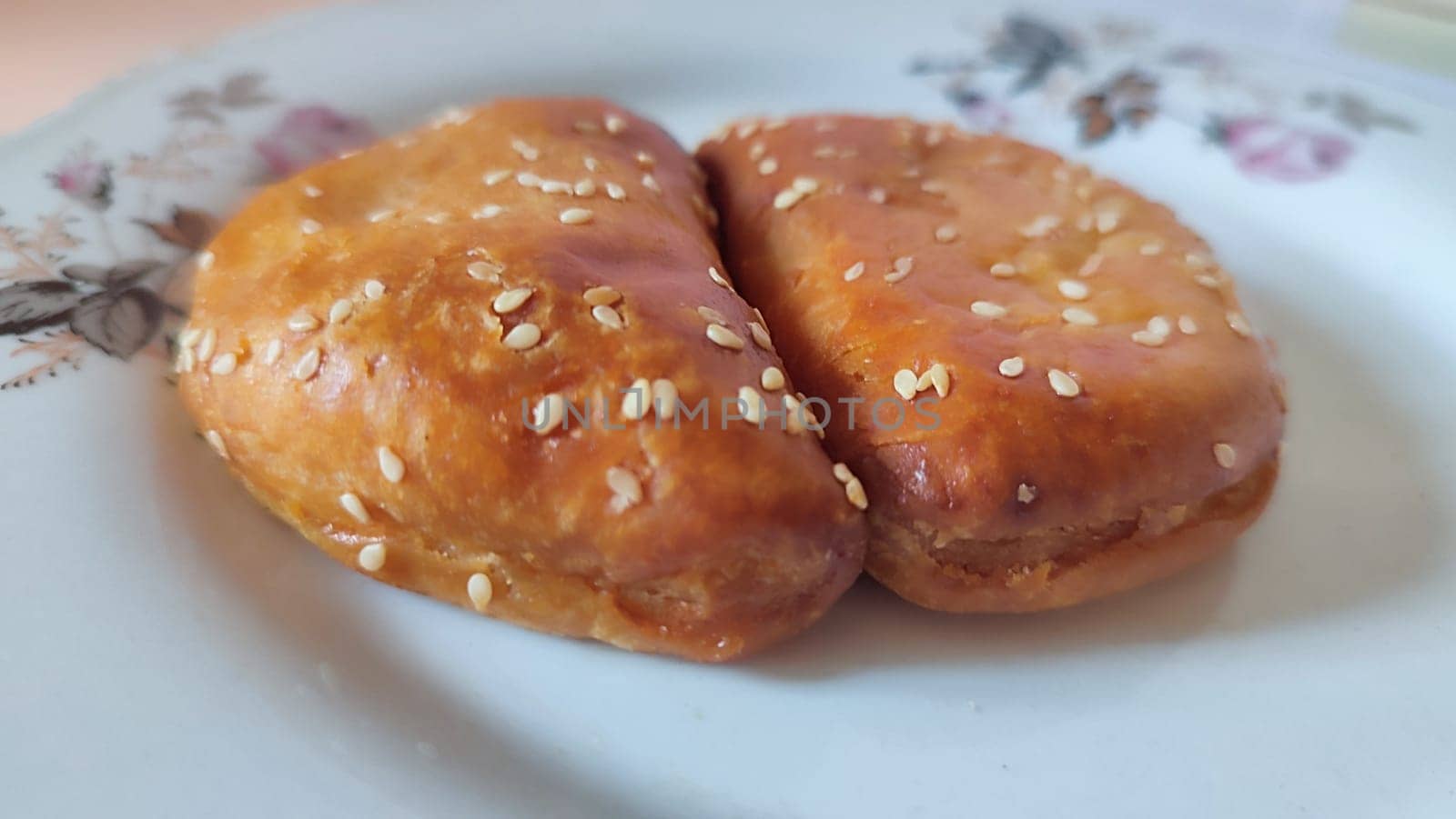 dough pies with sesame seeds on a white plate, food baking cooking. High quality photo
