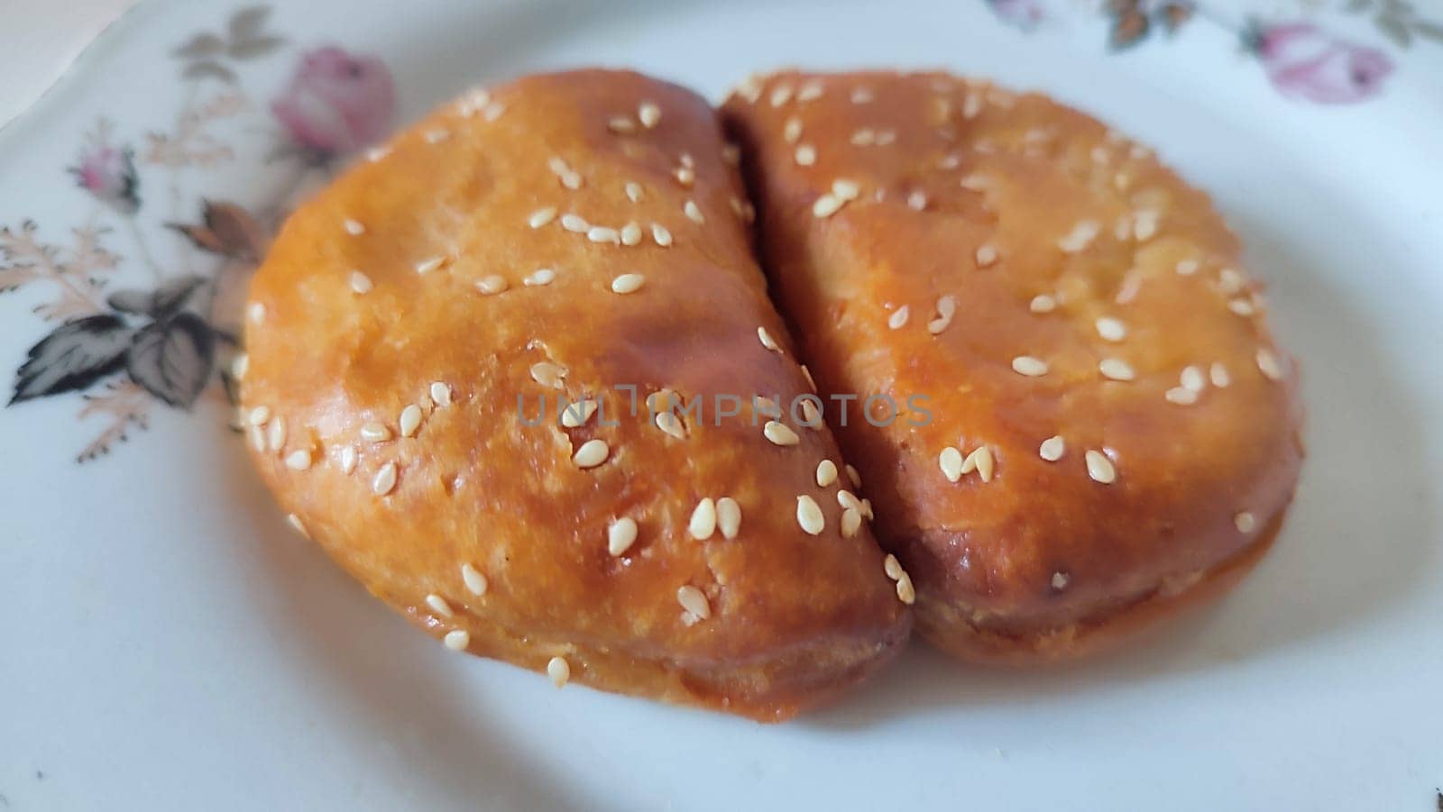 dough pies with sesame seeds on a white plate, food baking cooking. High quality photo