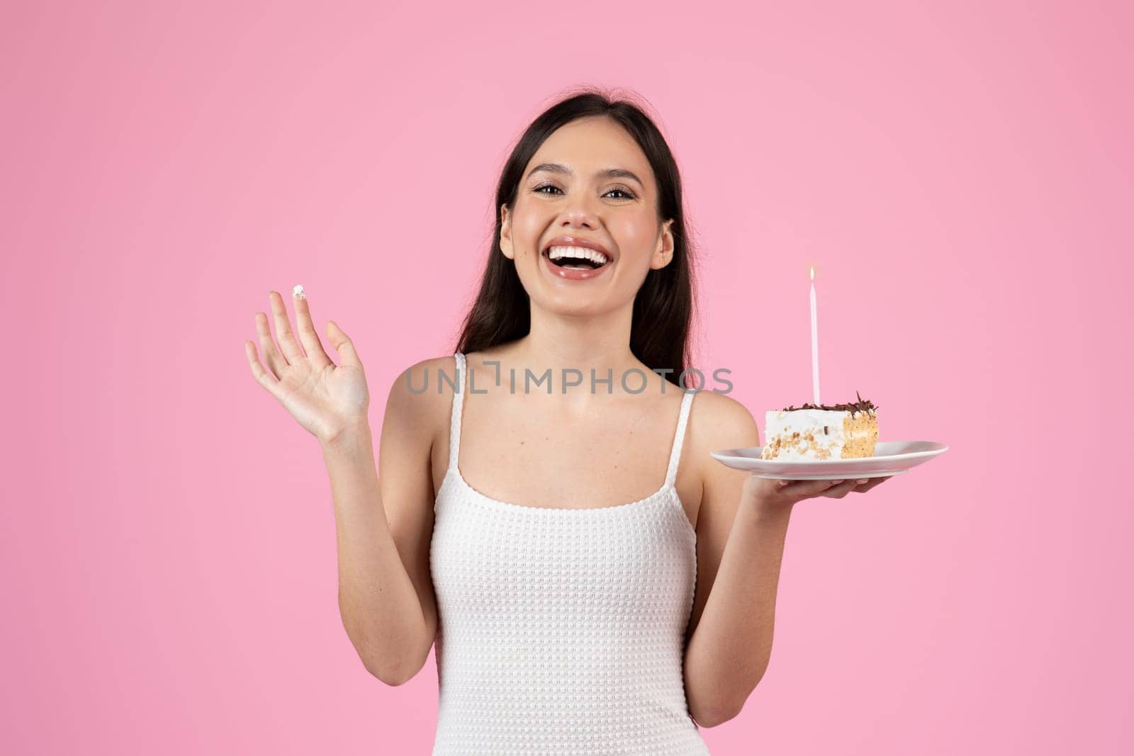 Exuberant lady laughing whilst holding a birthday cake, set against a pink backdrop of European summer, isolated and fit for generation z