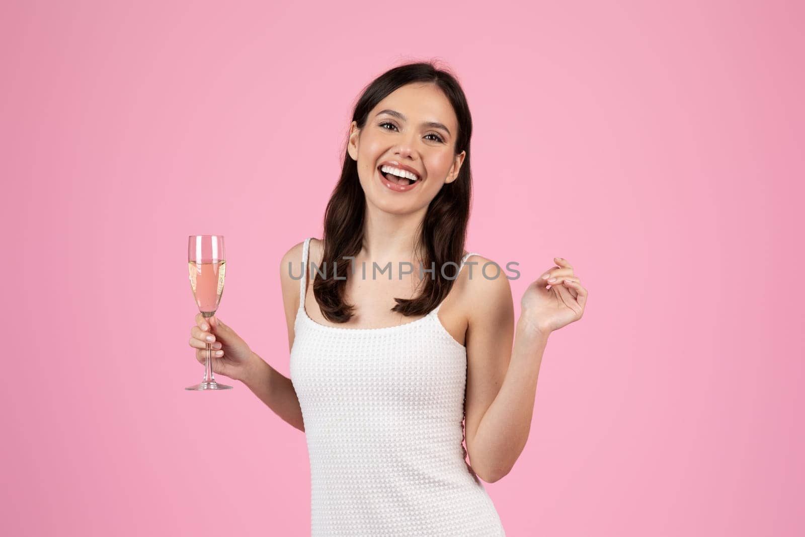 An exuberant lady holding a flute of champagne, embodying the spirit of celebration and summer, ideal for Generation Z imagery, isolated on pink