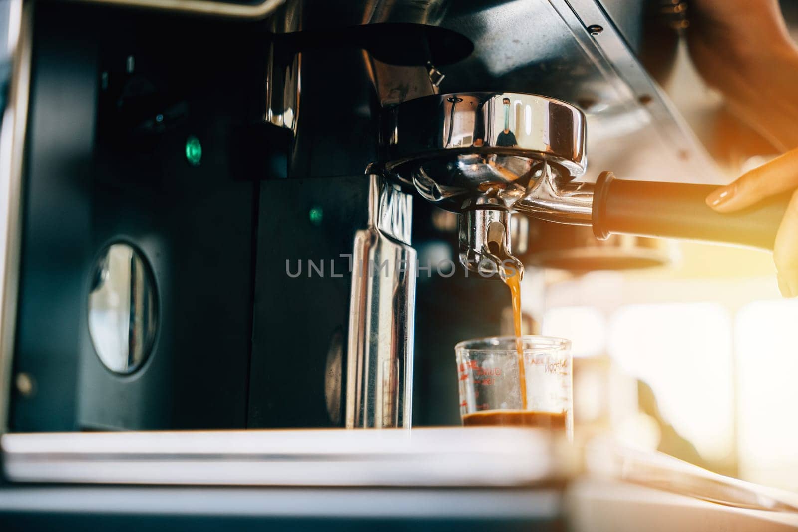 In a coffee shop espresso machine brews coffee. Fresh espresso pouring into glasses displaying modern coffee making technology. Flowing liquid steam smooth service in cafe.