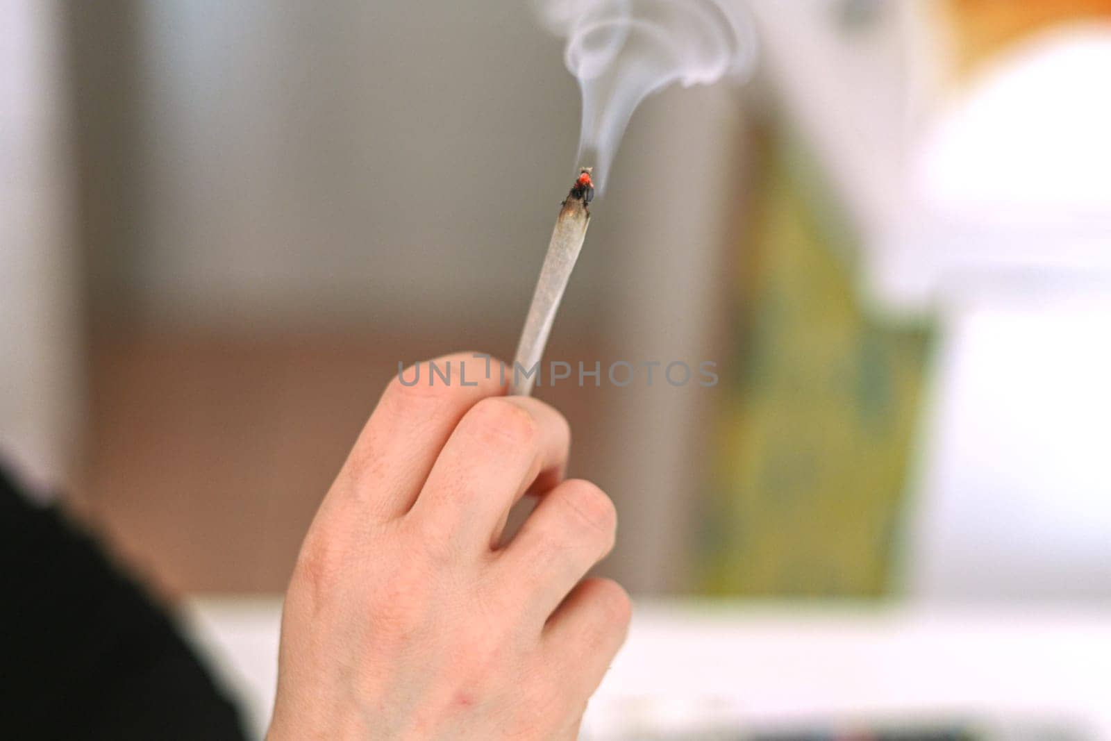 unrecognizable person prepare smoke hashish tobacco cigarette joint personal health relax use at home by verbano