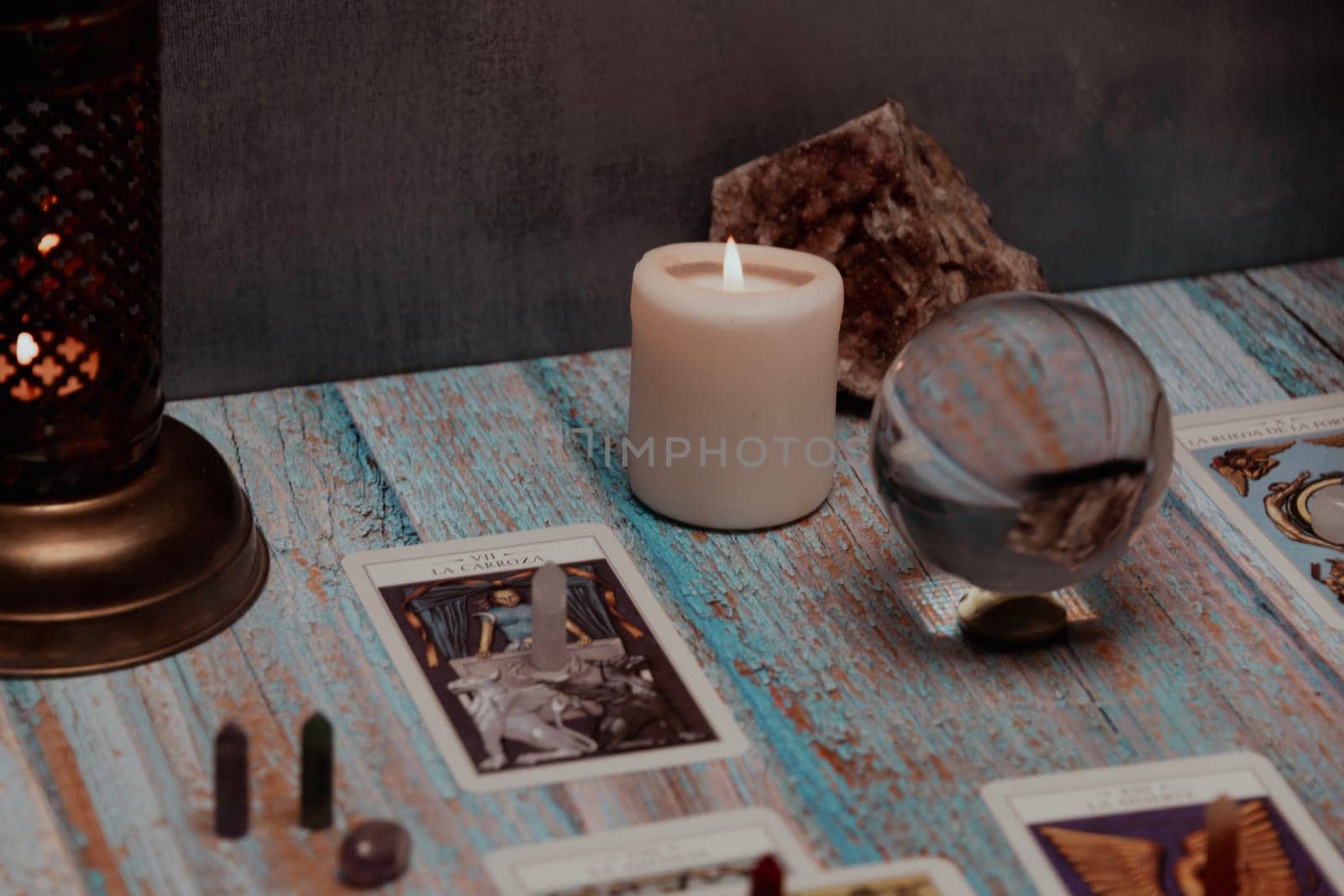 A tarot card reading session depicted with candles, crystals, and mystical accessories on a rustic wooden table