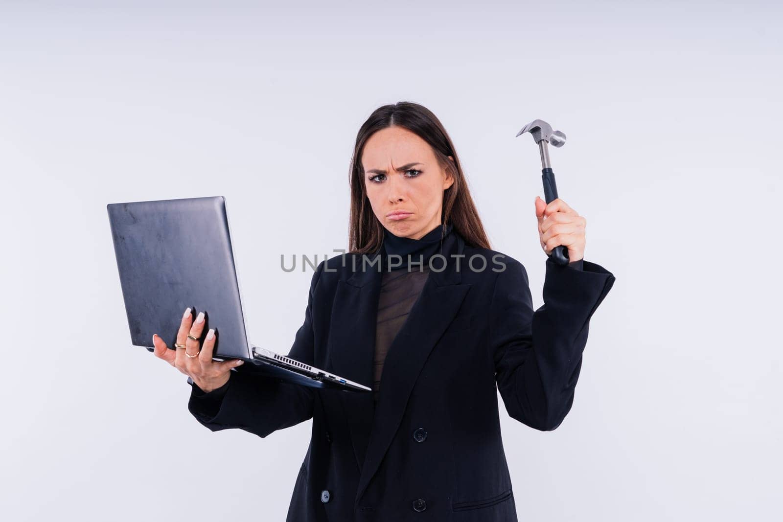 Attractive woman wearing business suit with computer angry facial expression holding a hammer by Zelenin