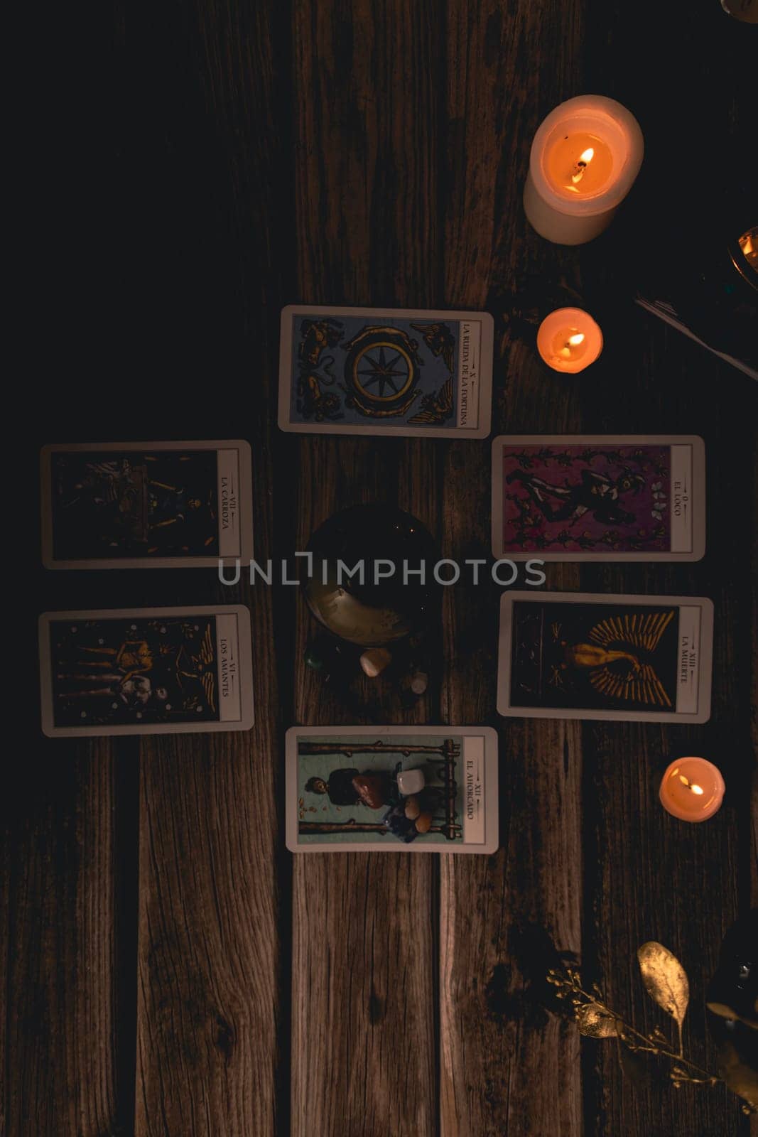 Tarot cards including The Fool and The Lovers alongside crystals and candles on a textured wooden table