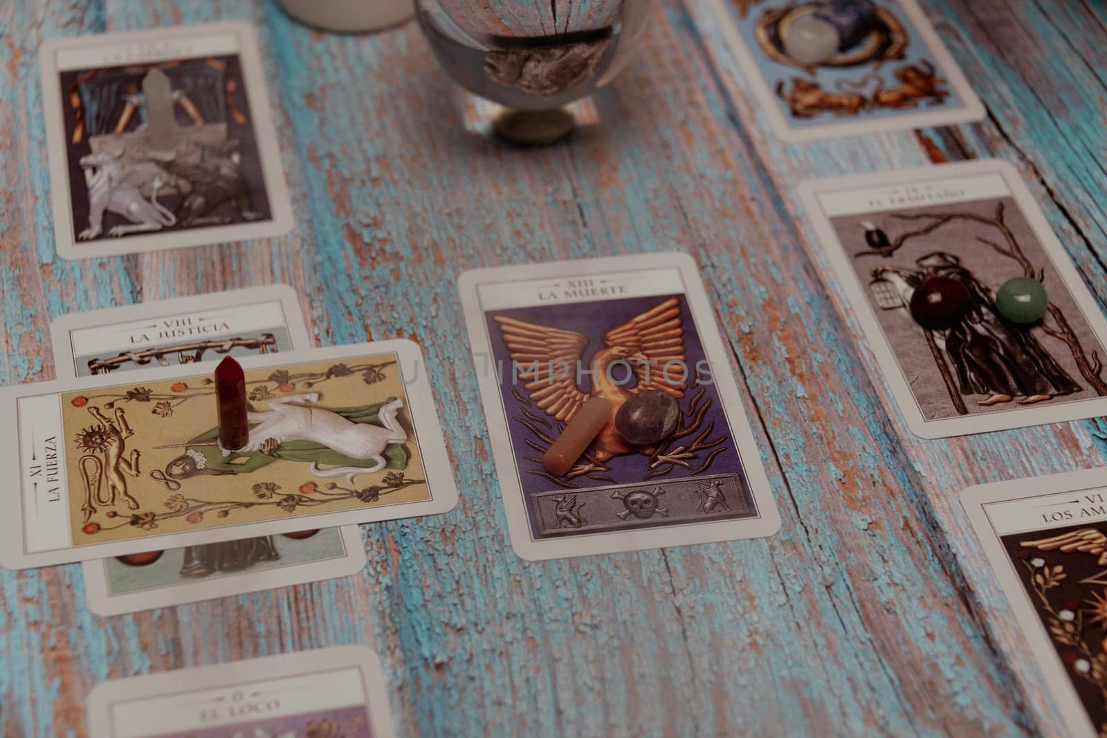 A tarot card reading session depicted with candles, crystals, and mystical accessories on a rustic wooden table