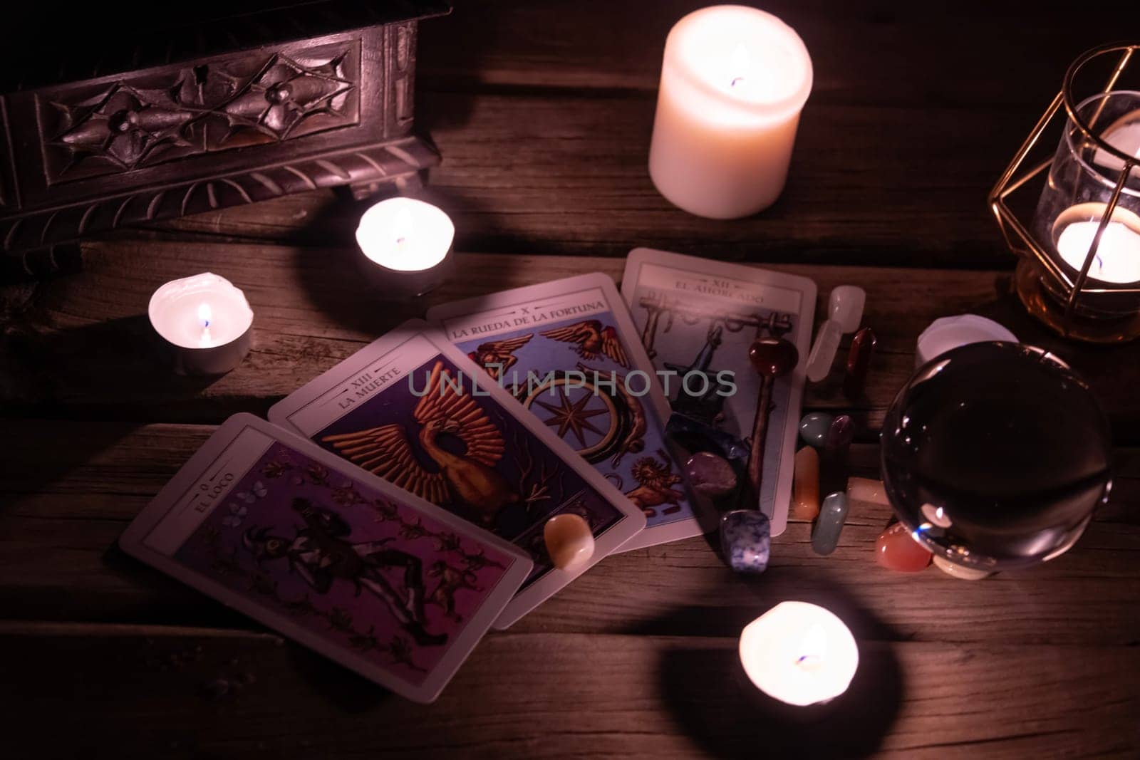 Tarot cards including The Fool and The Lovers alongside crystals and candles on a textured wooden table
