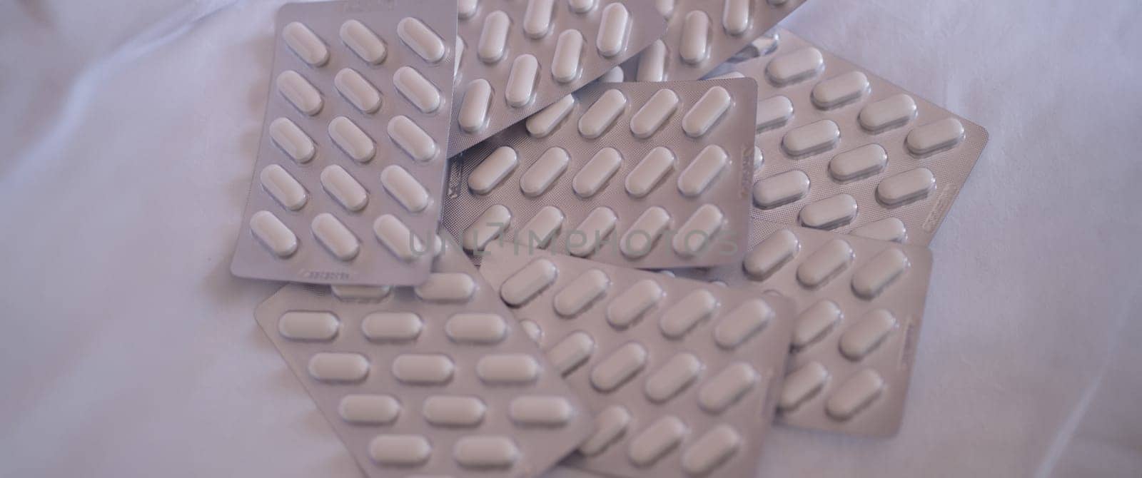 Pile of medical pills in blister pack closeup by kuprevich