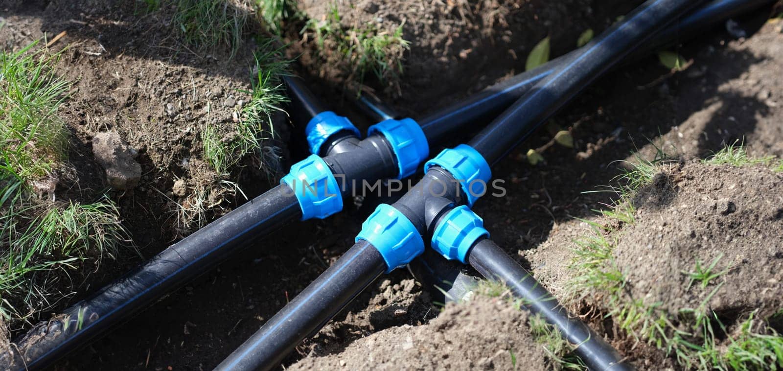 Connecting HDPE plastic water pipes in garden closeup by kuprevich