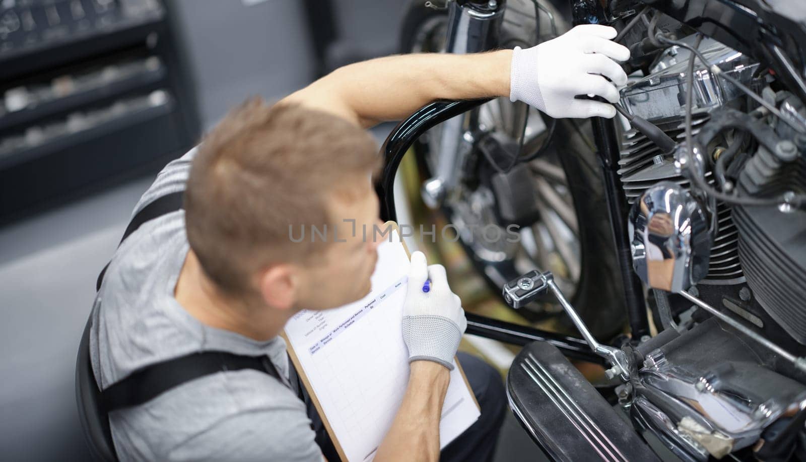 Car mechanic inspects motorcycle breakdowns in car repair shop by kuprevich
