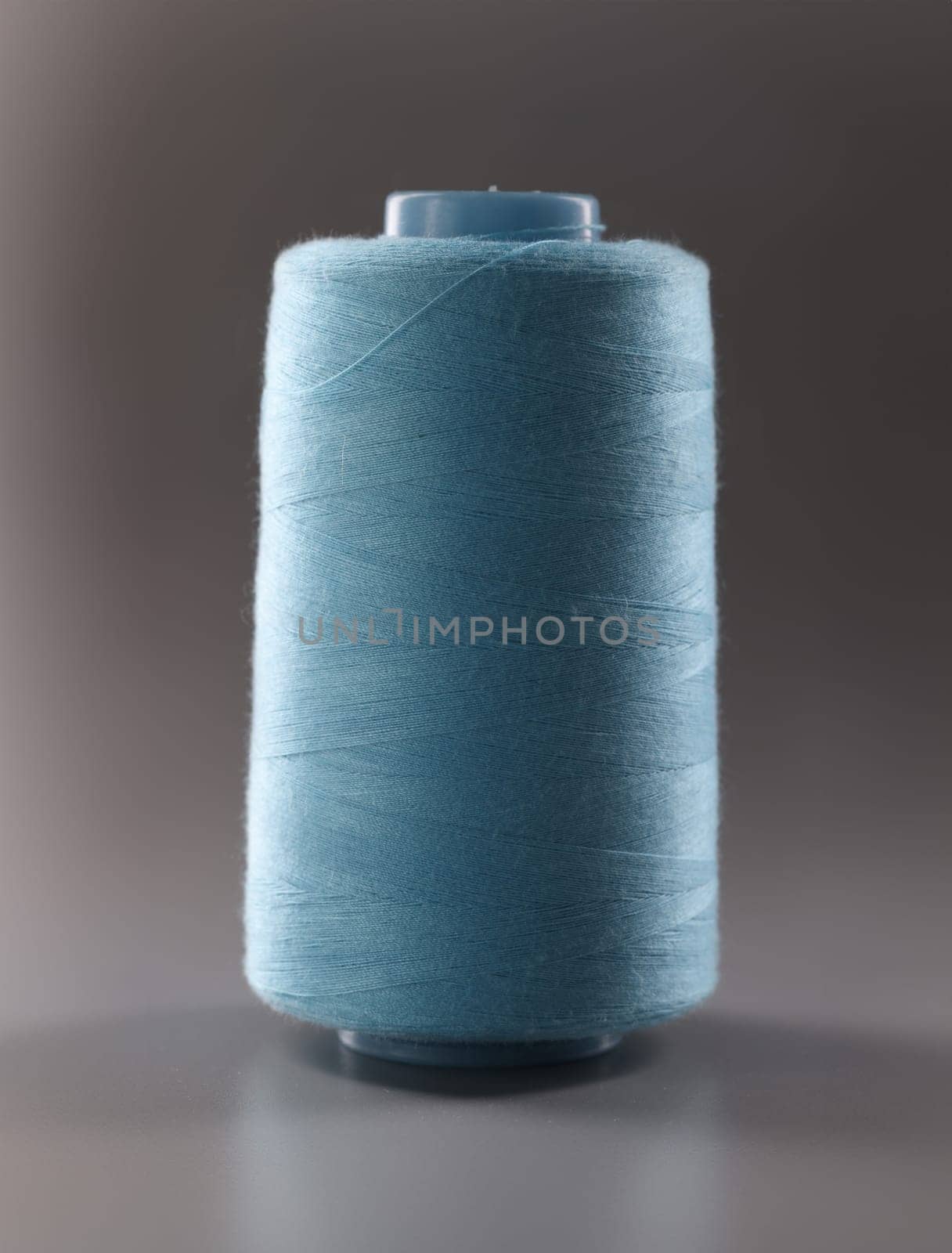 Texture of blue thread in sewing spool on gray background. closeup by kuprevich