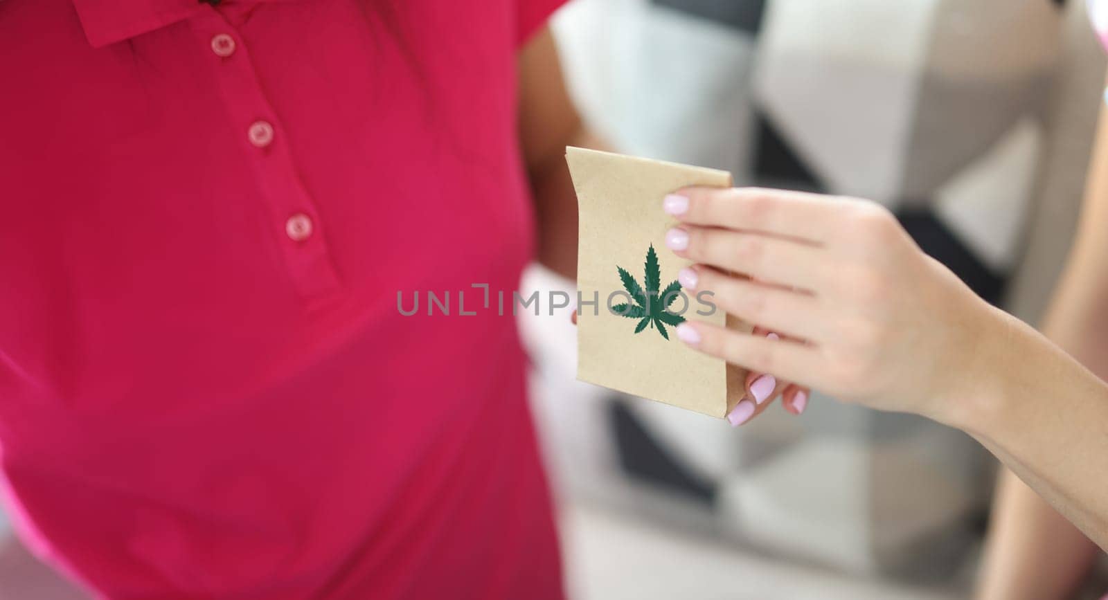 Woman hand passes paper bag with and marijuana closeup by kuprevich
