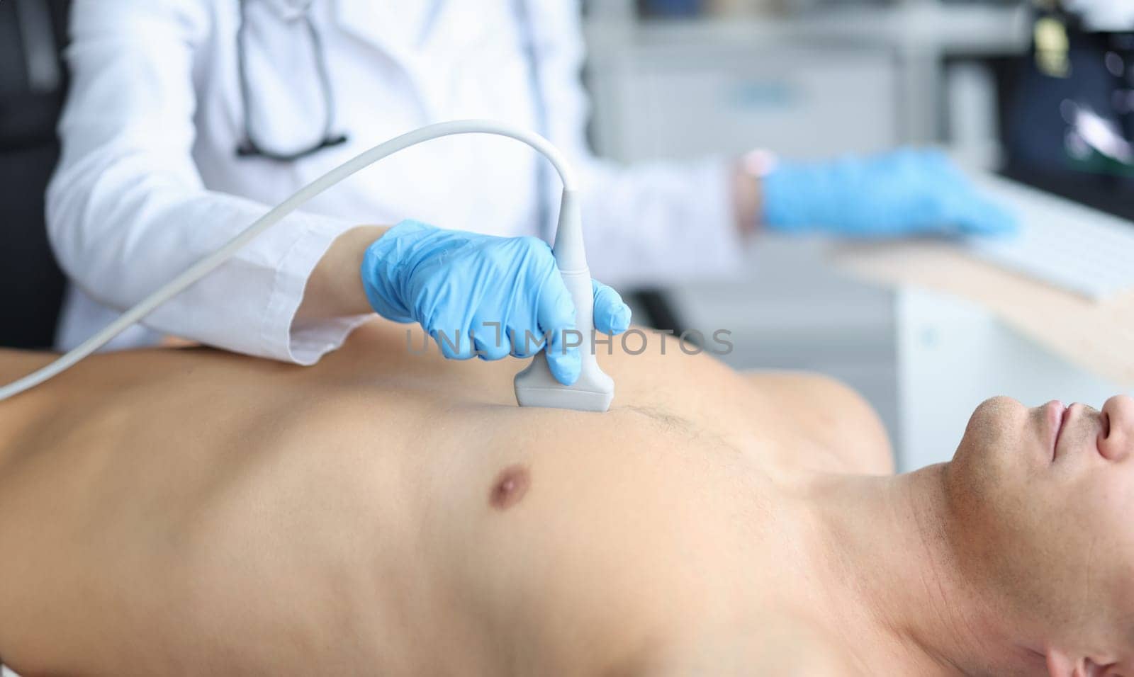 Doctor holding ultrasound machine on man chest in clinic. Checking patient's heart health and cardiology