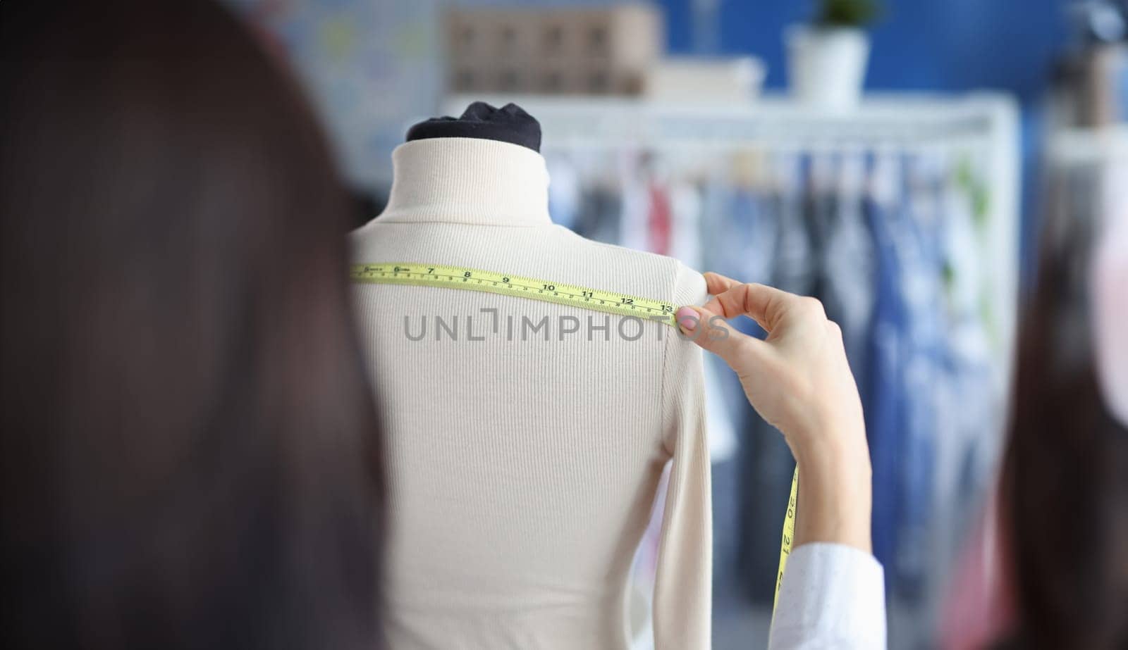 Fashion designer stylist takes measurements with centimeter from clothes on mannequin. Atelier services concept