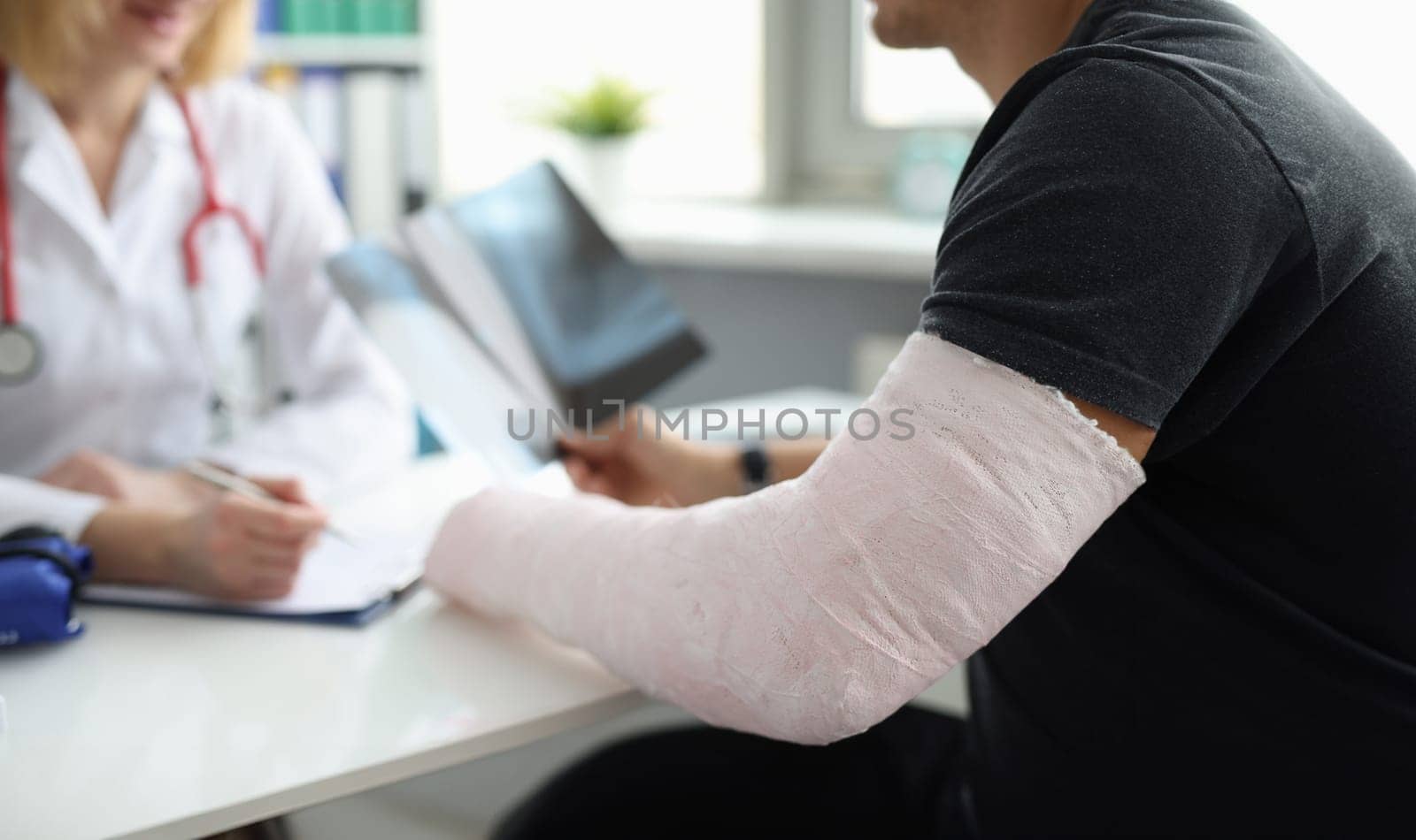 Doctor conducts medical consultation with patient with cast on arm by kuprevich