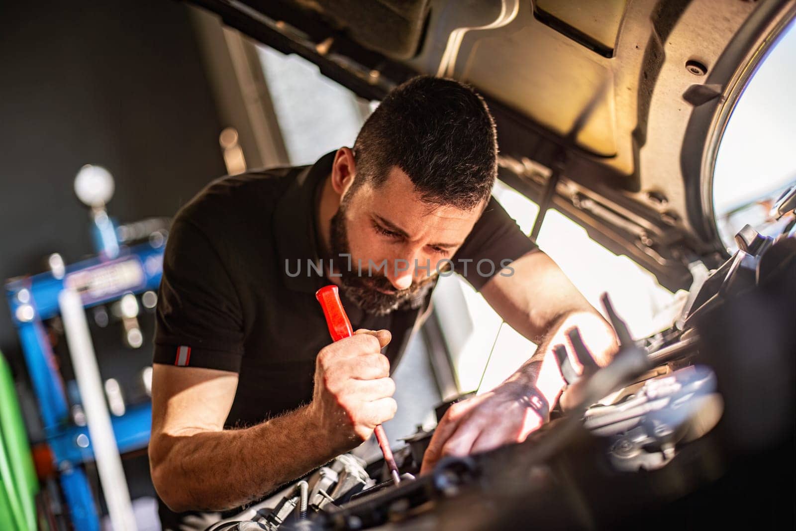 Milan, Italy 9 April 2024: Mechanic's hands delve into car engine under the hood, symbolizing repair and maintenance.