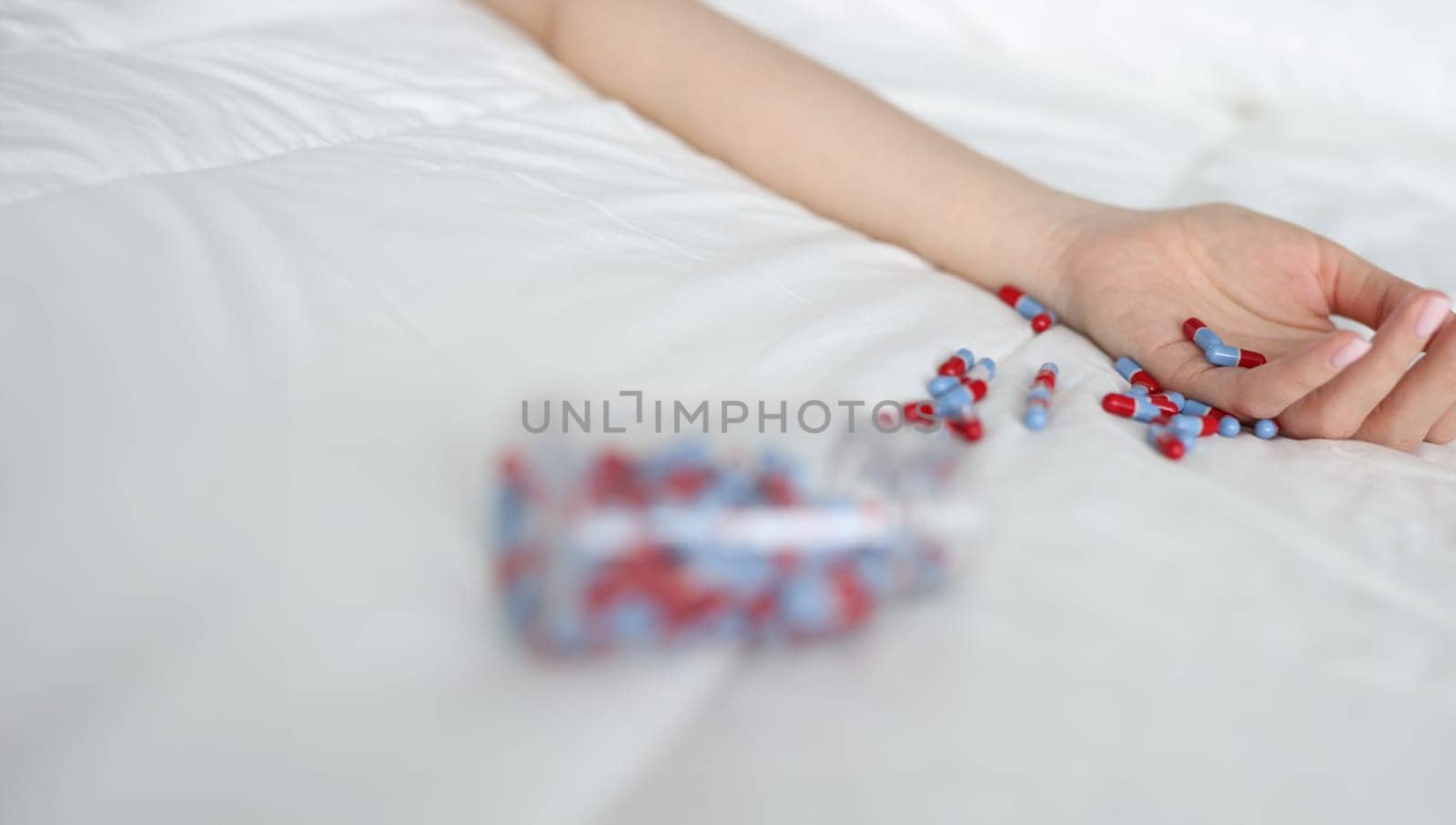 Woman hand after overdose of medical pills on bed. Medical consequences of abuse of sleeping pills concept