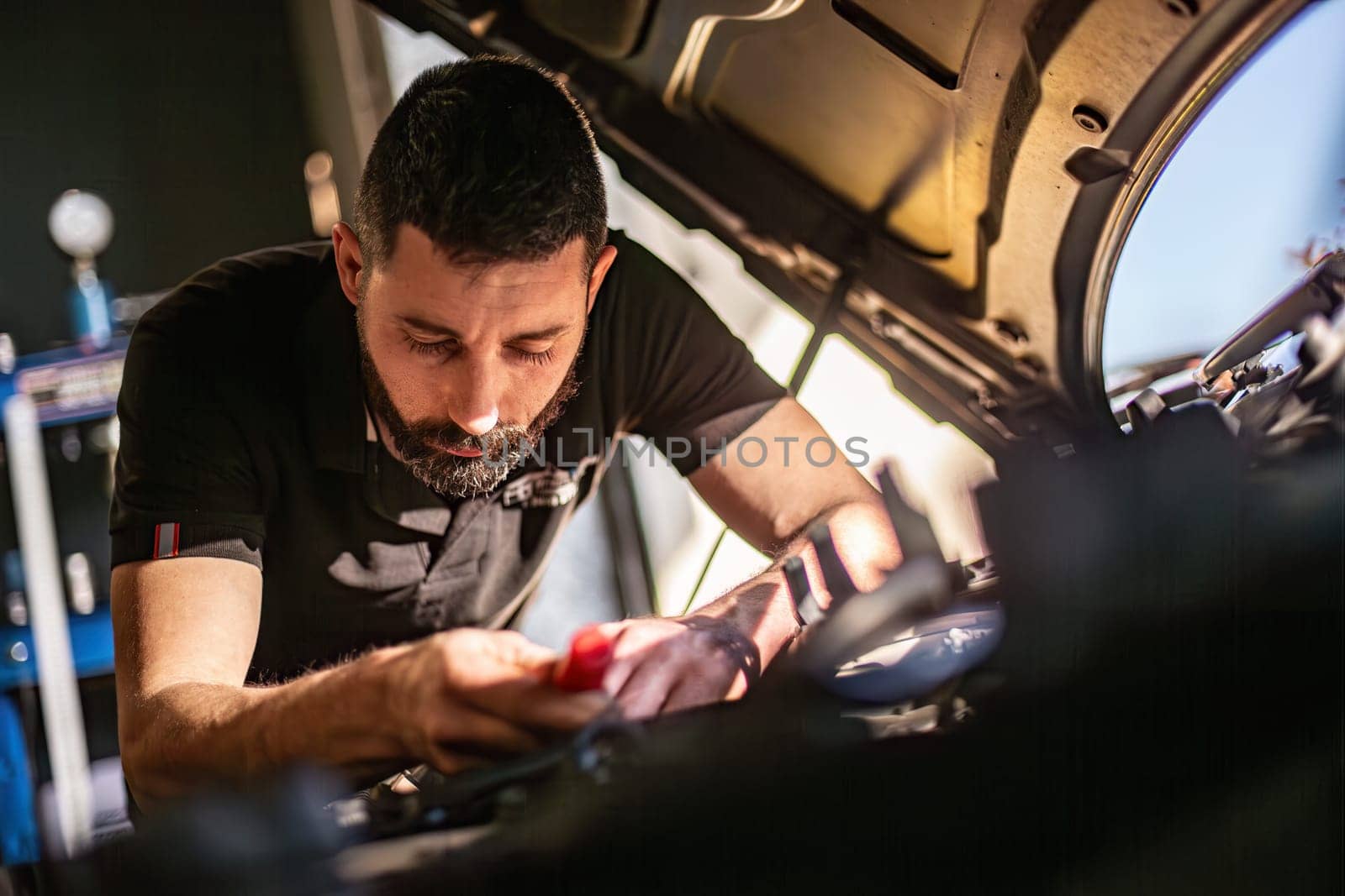 Milan, Italy 9 April 2024: Mechanic's hands delve into car engine under the hood, symbolizing repair and maintenance.