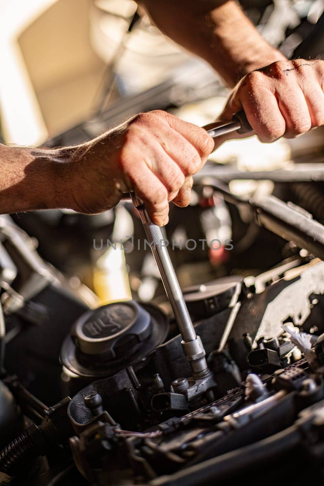 Milan, Italy 9 April 2024: Close-up of a mechanic's dirty hands while repairing a car engine, showcasing hard work.