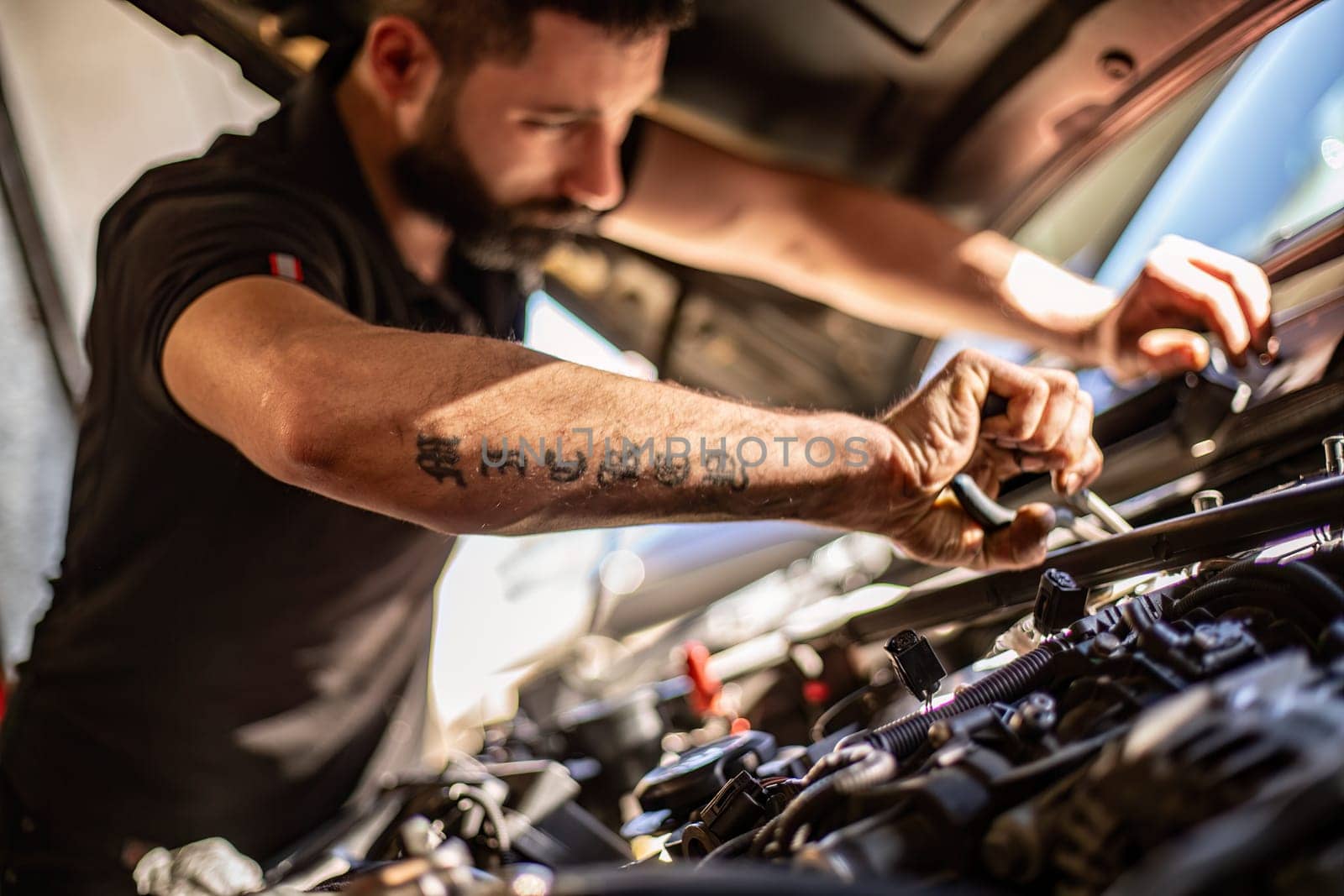 Milan, Italy 9 April 2024: Mechanic's hands delve into car engine under the hood, symbolizing repair and maintenance.