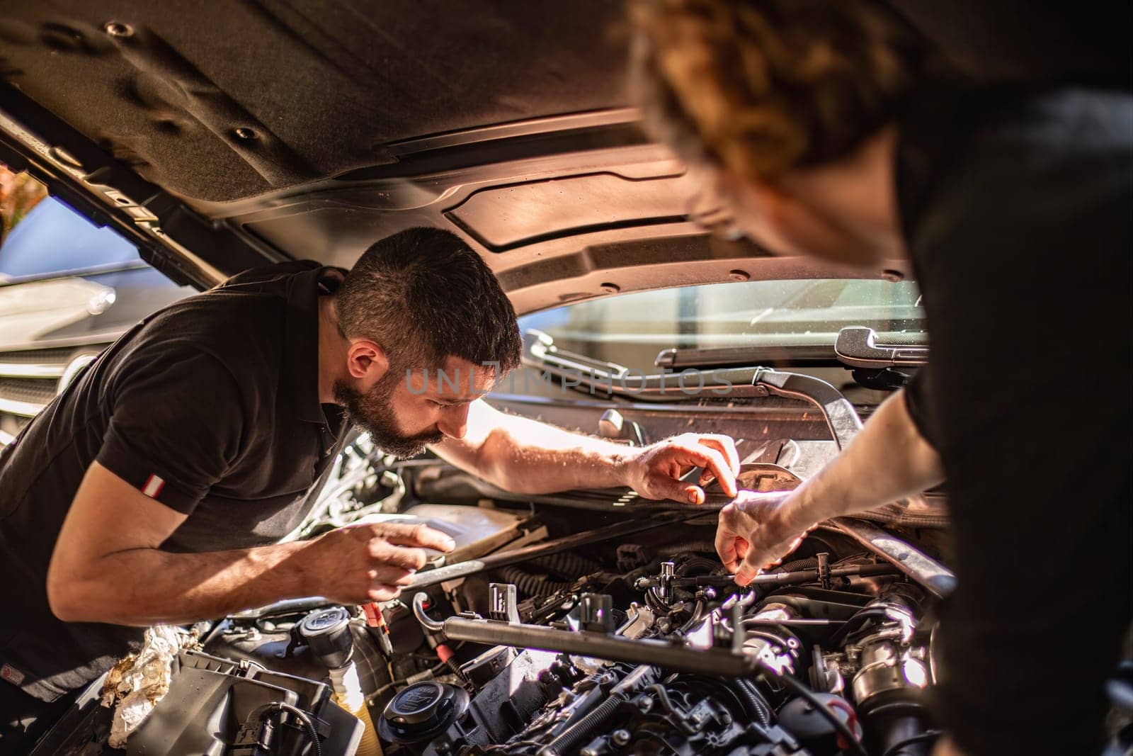 Milan, Italy 9 April 2024: Mechanic's hands delve into car engine under the hood, symbolizing repair and maintenance.