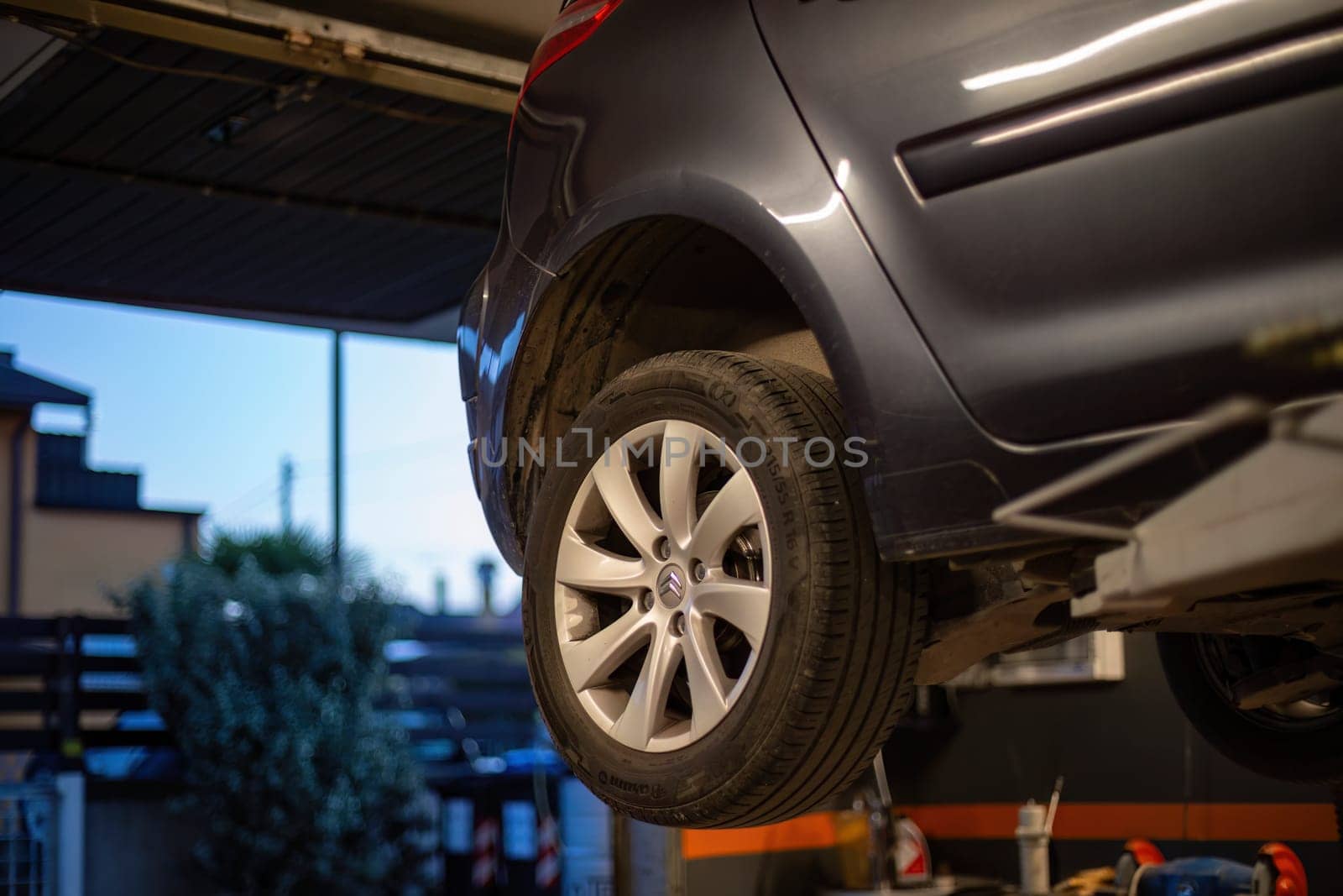 Milan, Italy 9 April 2024: car elevated on a lift inside a mechanical workshop, ready for maintenance and repair.