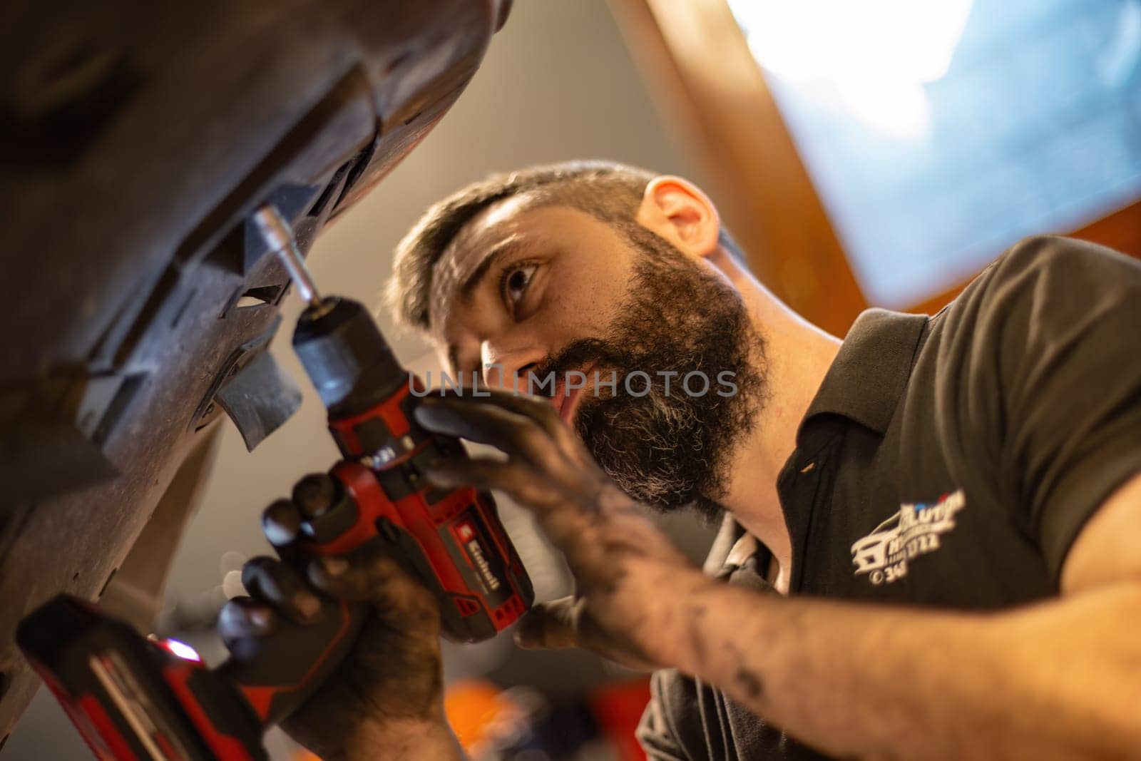 Milan, Italy 9 April 2024: Mechanic's hands delve into car engine under the hood, symbolizing repair and maintenance.