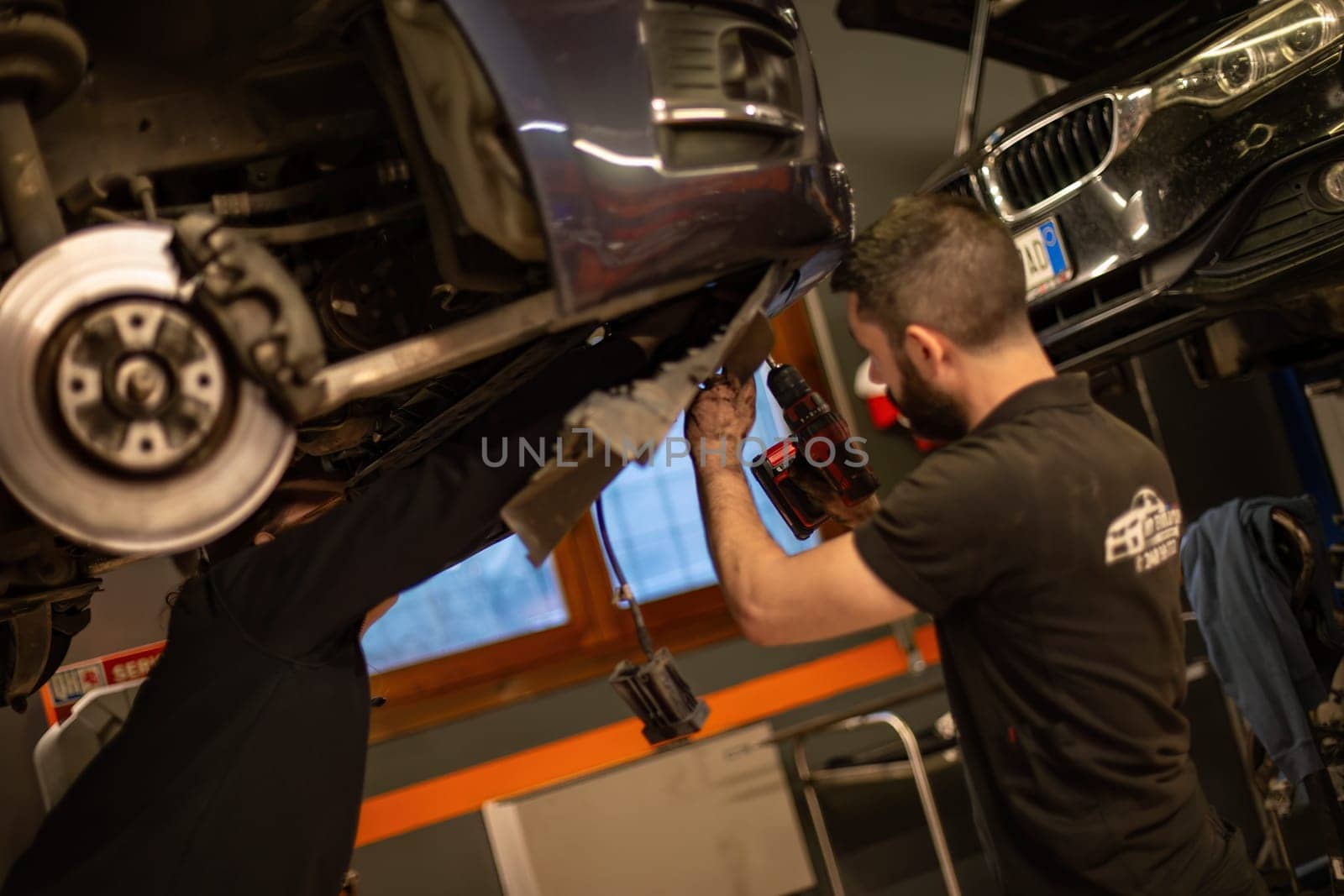 Milan, Italy 9 April 2024: Mechanic's hands delve into car engine under the hood, symbolizing repair and maintenance.