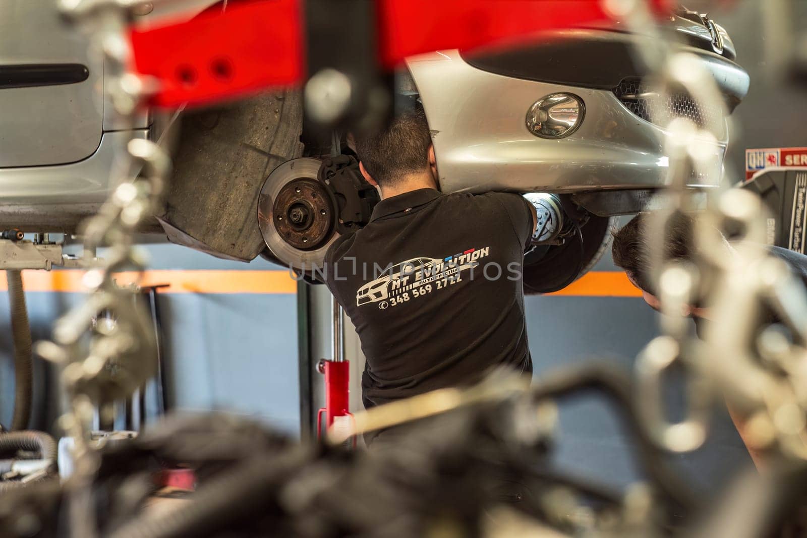 Milan, Italy 9 April 2024: Mechanic's hands delve into car engine under the hood, symbolizing repair and maintenance.