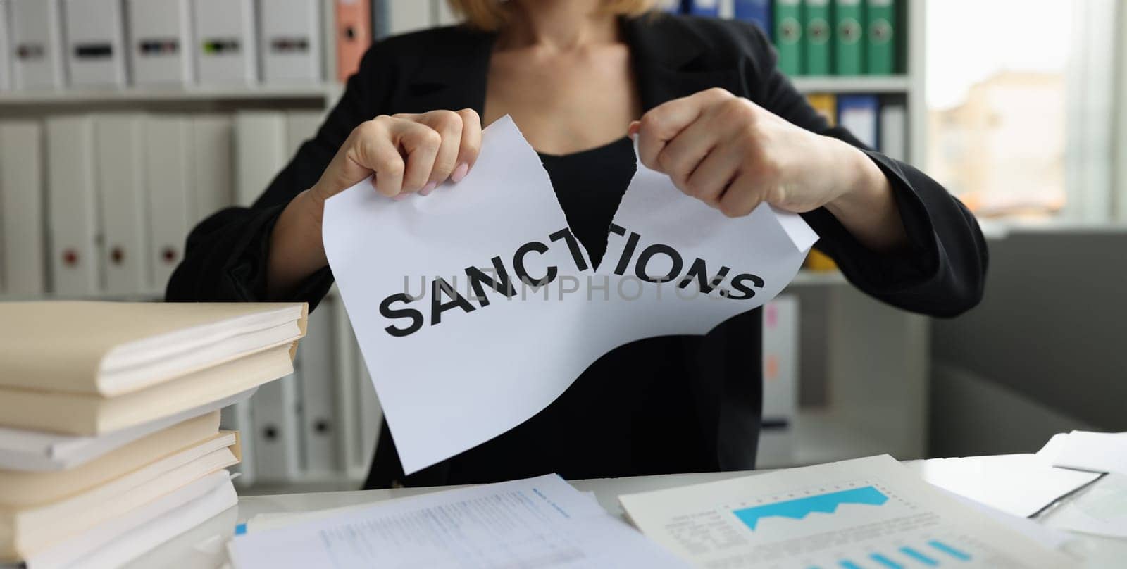 Businesswoman tears up sheet of paper with sanctions inscription. Economic sanctions against business concept