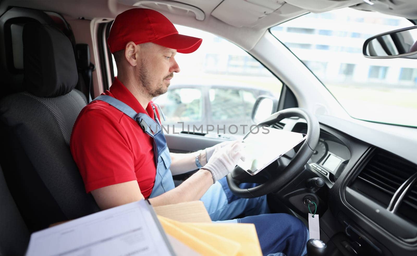 Portrait of courier driver using digital tablet sitting in van. Delivery service and delivery concept