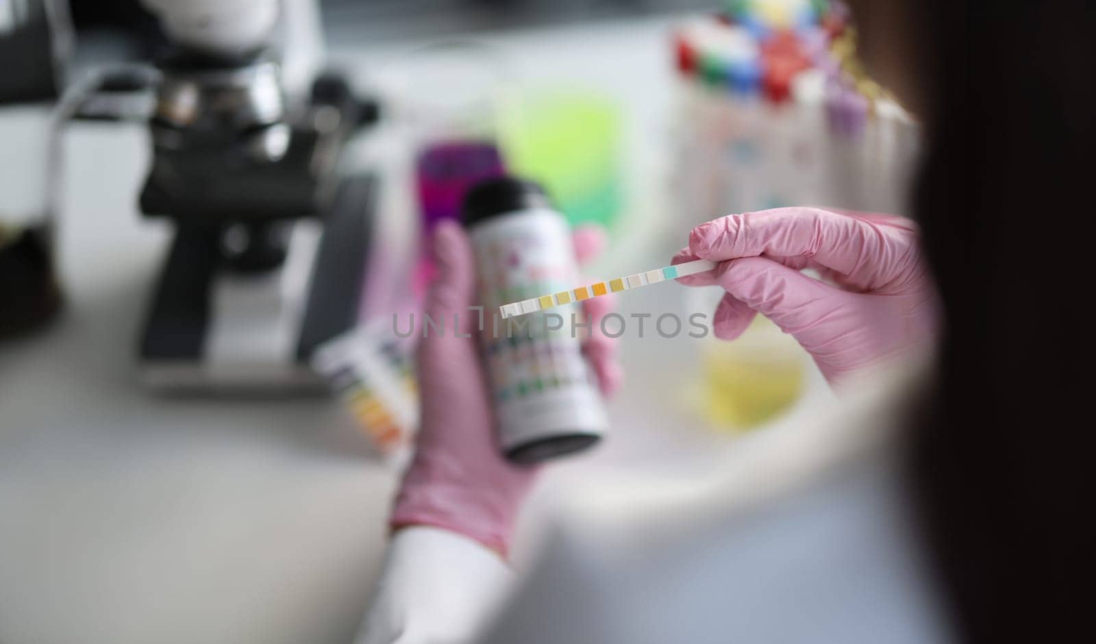 Chemist in laboratory checks ph strips closeup by kuprevich