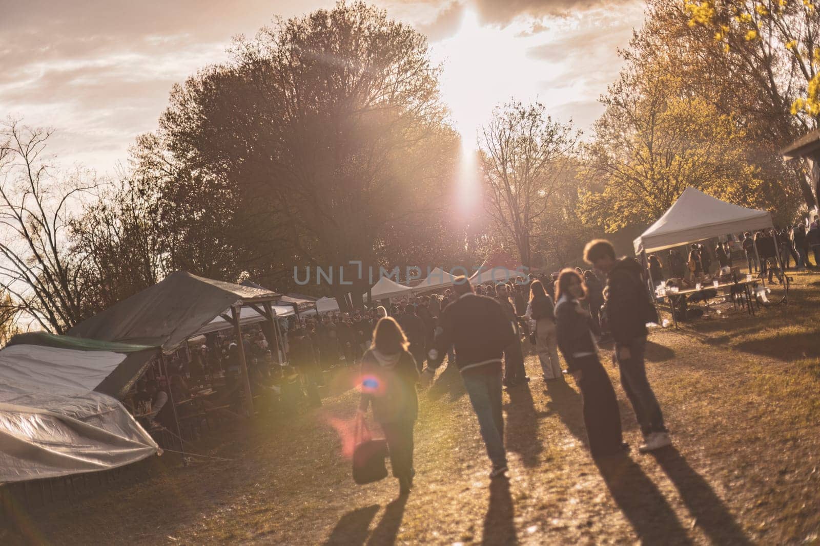 Milan, Italy 1 April 2024: A vibrant sunset rave party in a park, showcasing energetic silhouettes dancing.