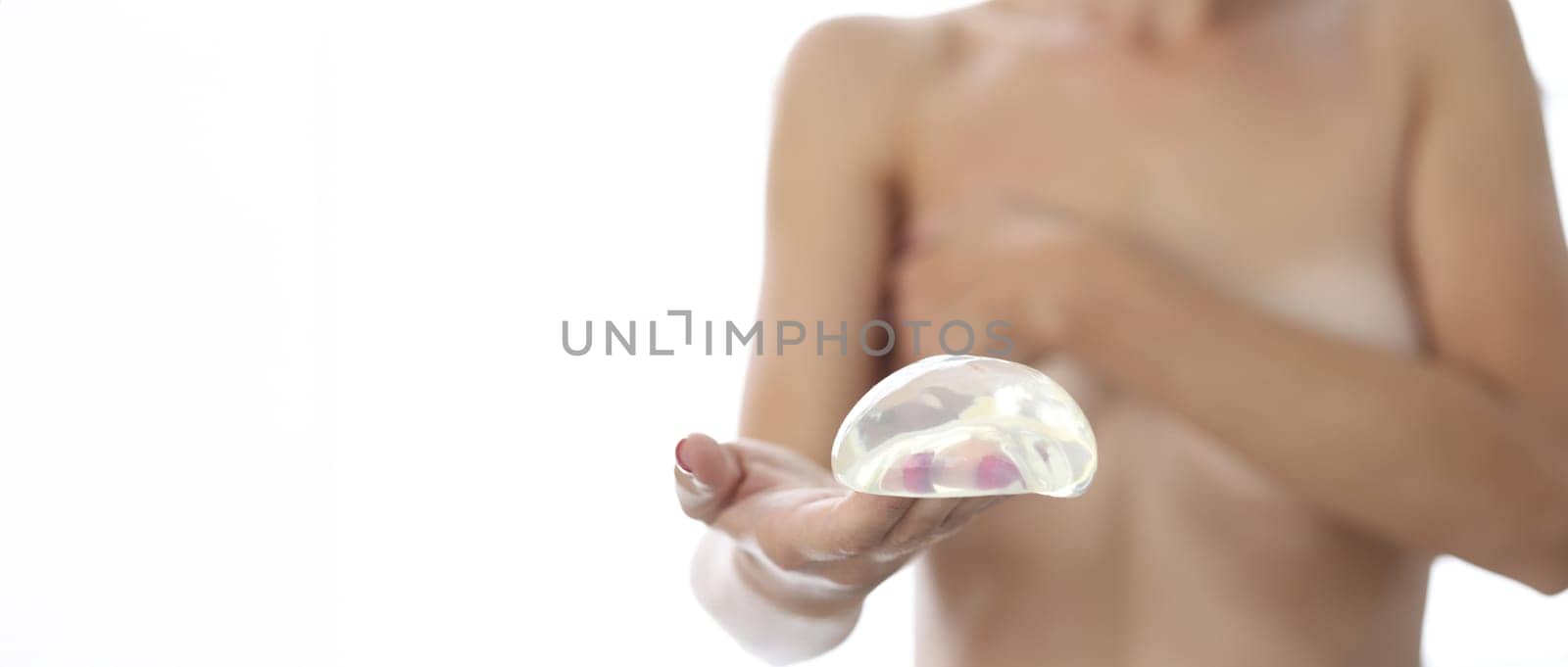 Woman holds silicone breast implant for breast augmentation. Plastic surgery concept