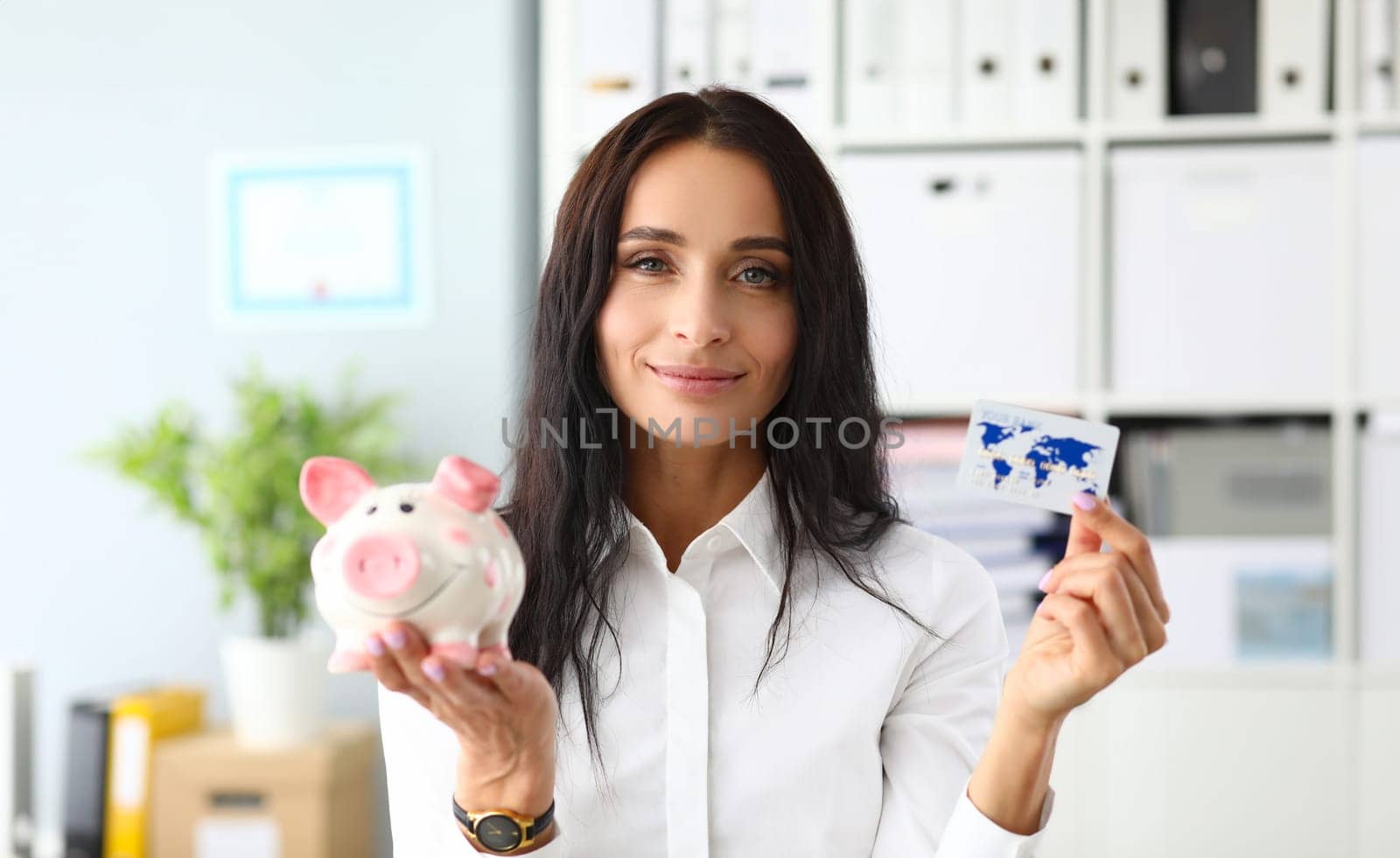 Smiling woman holding piggy bank and bank card by kuprevich