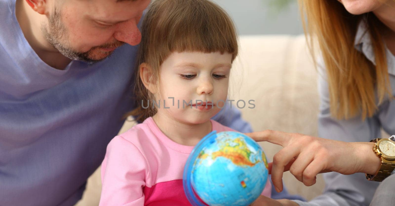 Parents show world globe to child. Traveling with kids concept