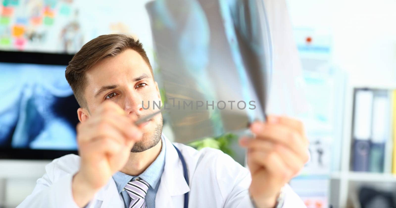 Male doctor examining x-ray in clinic closeup by kuprevich