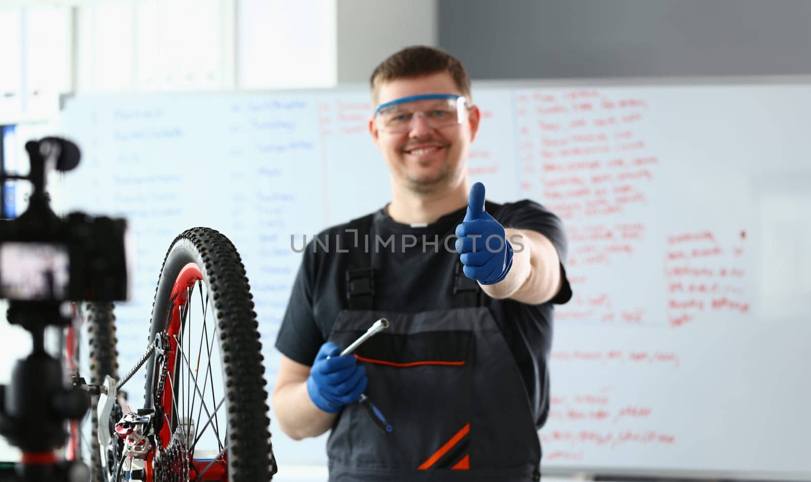 Bicycle repairman in workshop holding thumbs up by kuprevich