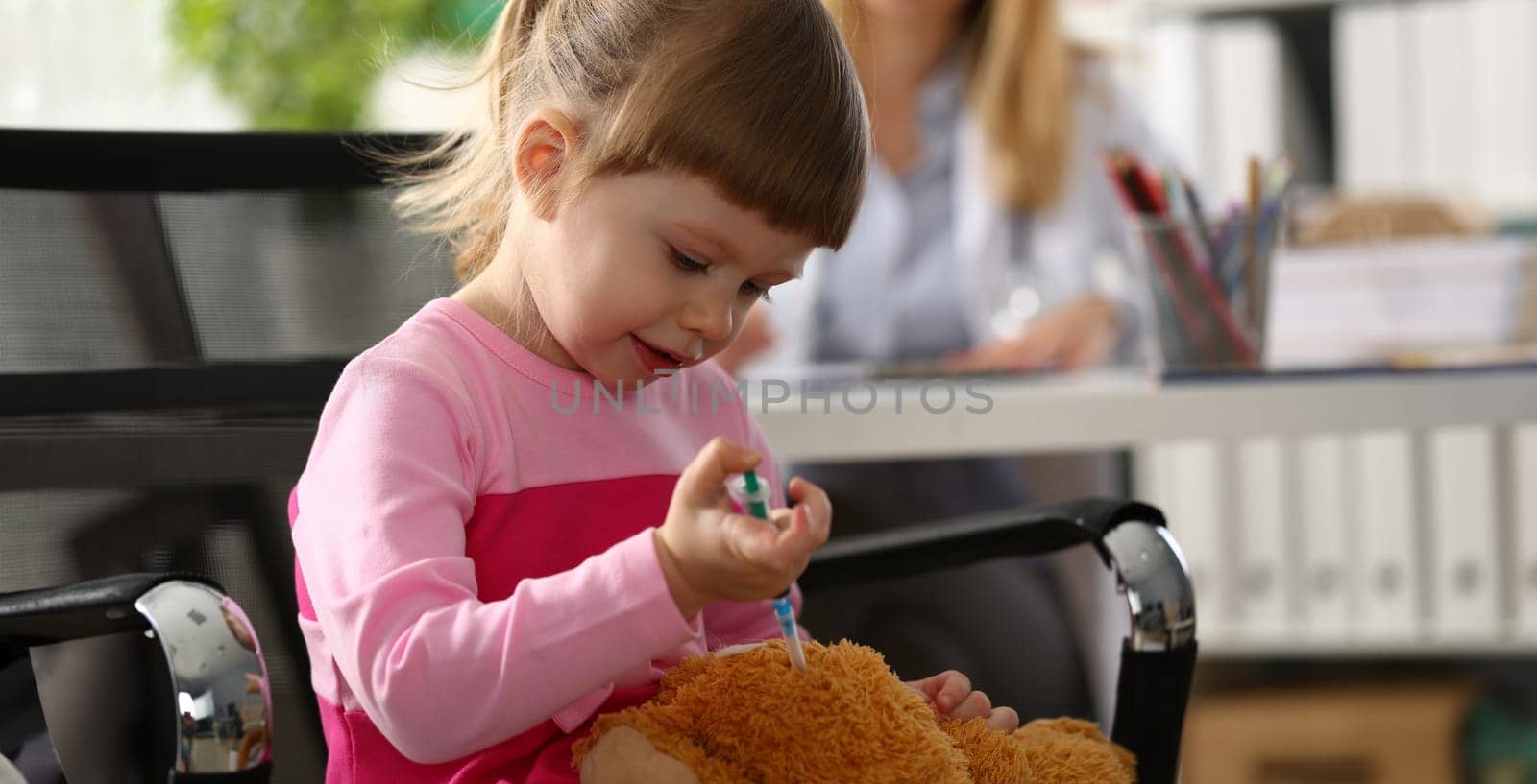 Little girl gives injection to toy closeup by kuprevich
