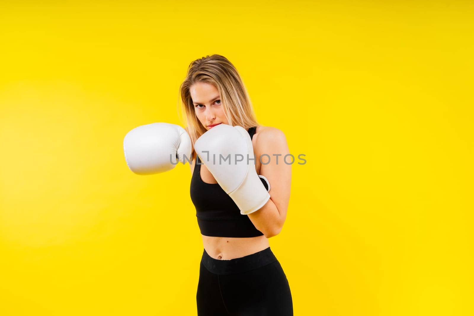 Female boxer hitting at a boxing studio. Woman in gloves training hard. by Zelenin