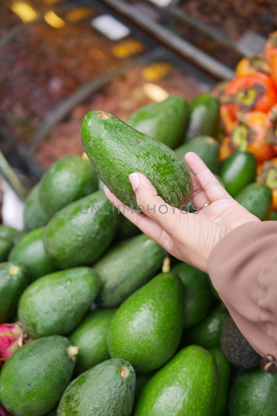 young woman hand holding avocado shopping at retail store .