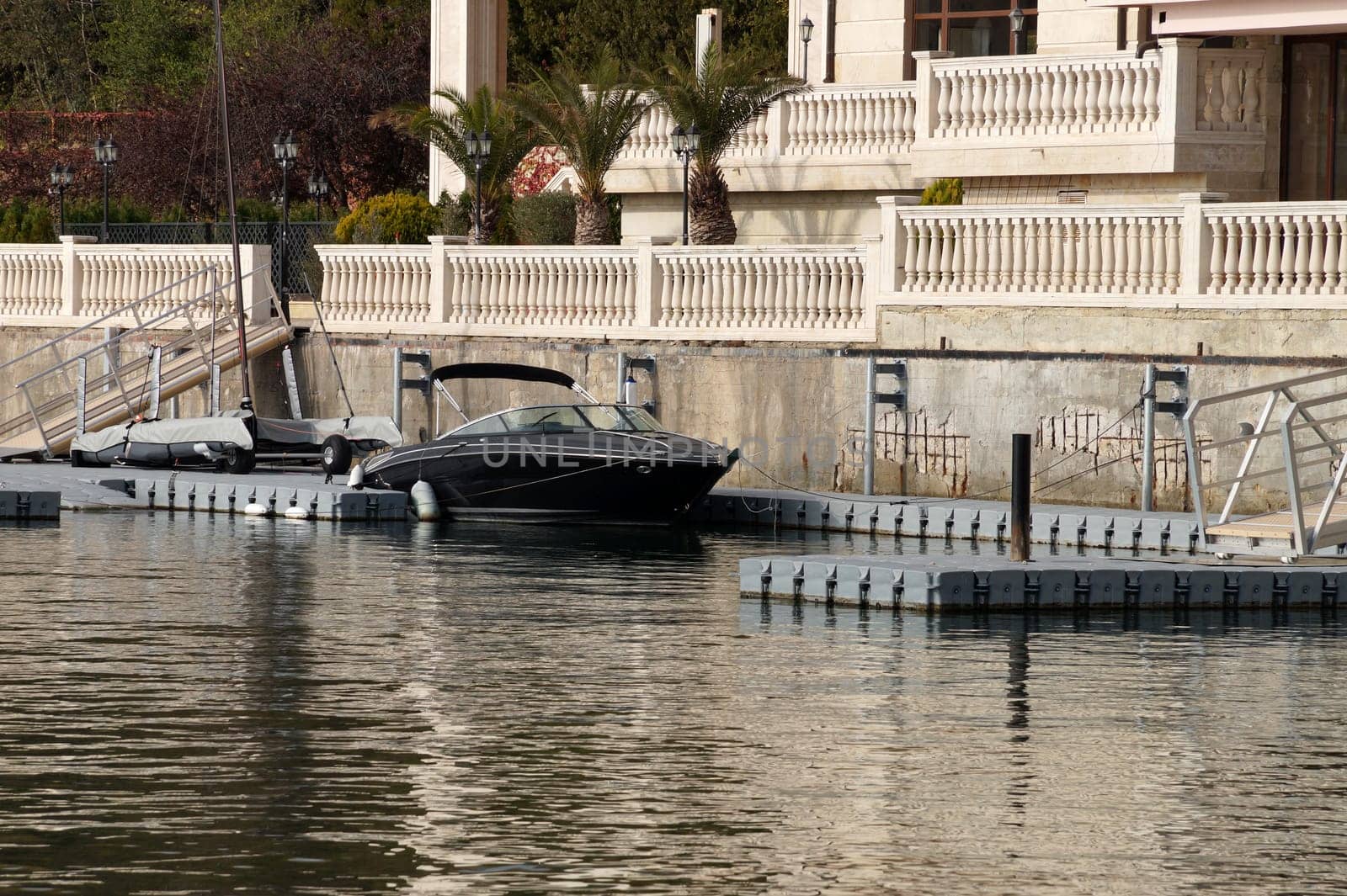 speedboat docked at a pier near a luxurious villa.
