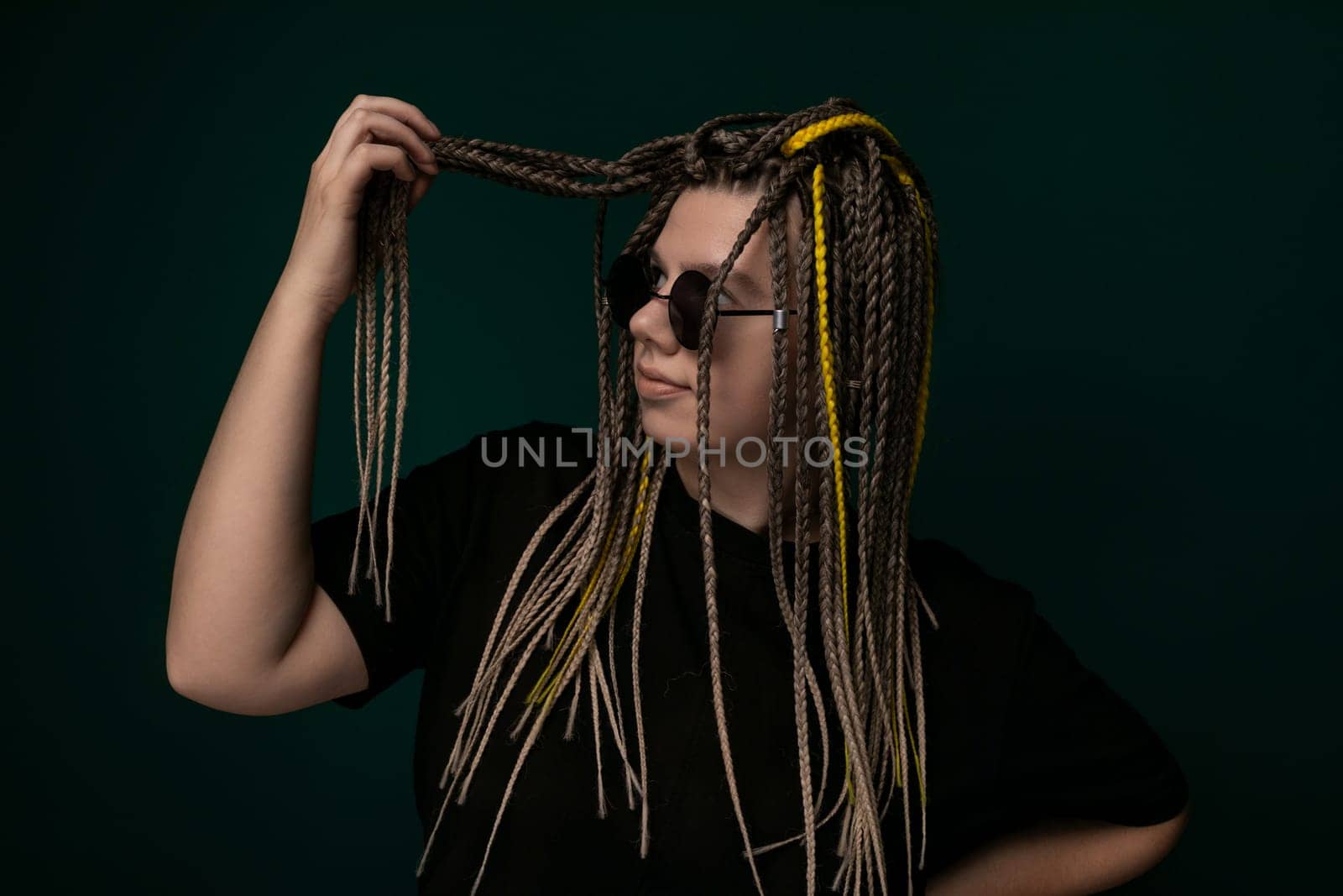 A woman with long, knotted dreadlocks on her head. She is looking off to the side, with a serene expression on her face. Her hair cascades down her back, showcasing the intricate texture of the dreadlocks.