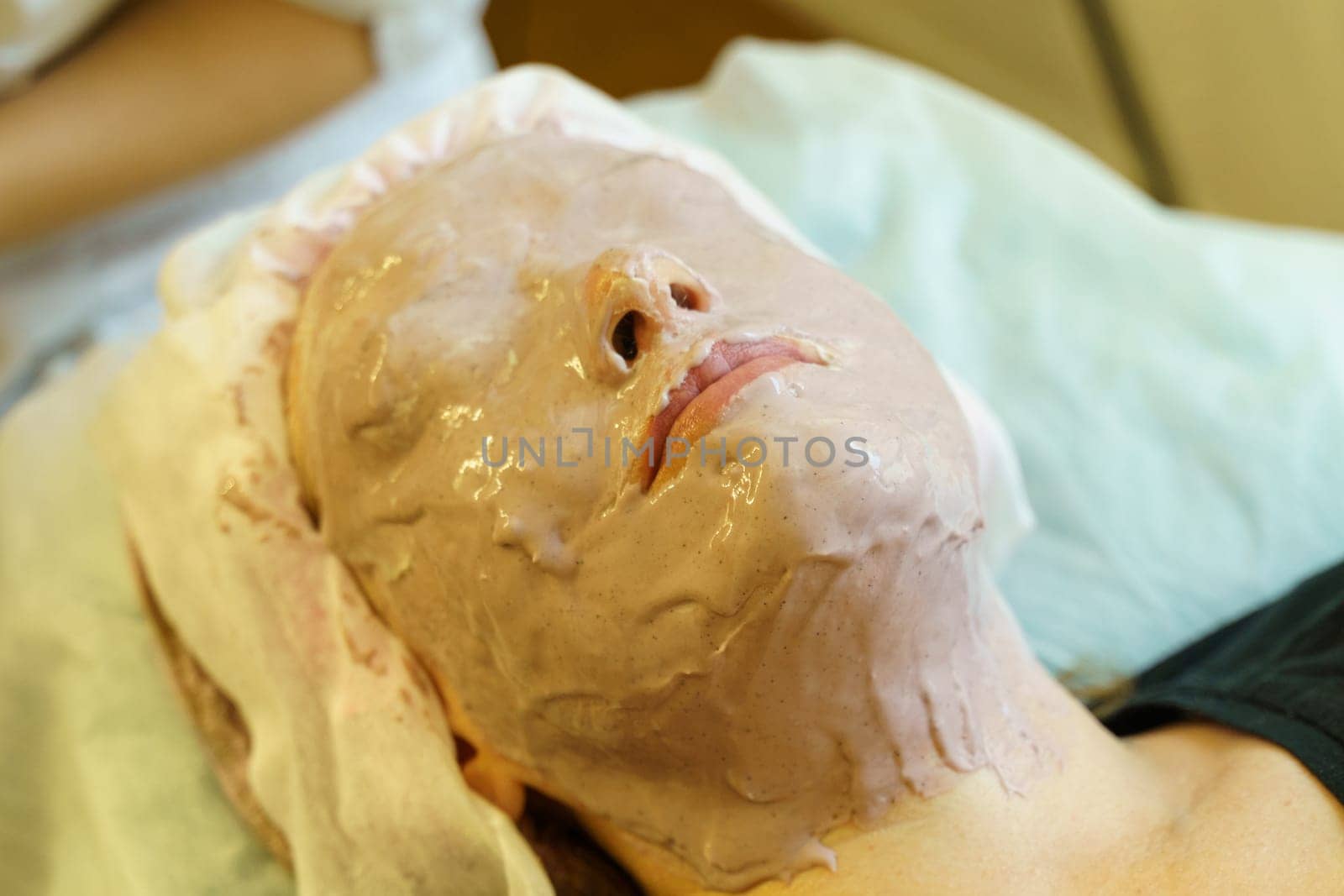 A woman having a facial mask applied during a skincare treatment at a beauty salon.